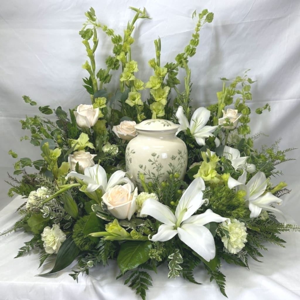 White lilies and cream roses arranged around a ceramic urn