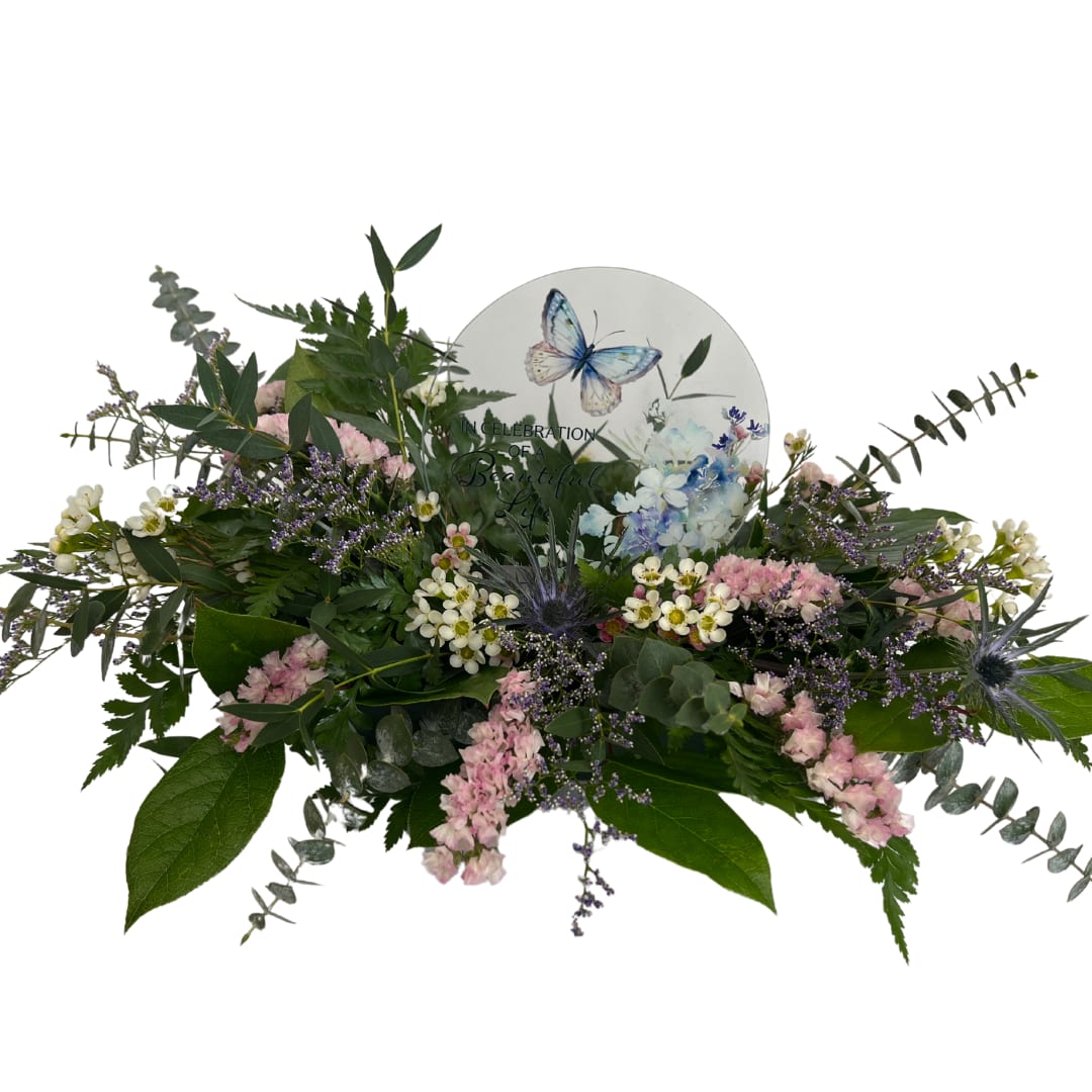 In Celebration Butterfly Sitter - Deluxe Arrangement Pictured - Our round sitters are made of full color UV printed glass and wood. The base measures 5/8"H x 4 1/4"W x 2"D. The glass measures 6"Dia x 1/16"Depth. Each pieces is designed and printed in the USA! Standard: Mixed greenery base Deluxe: Greenery base with small fillers added Premium: Upgraded floral base added