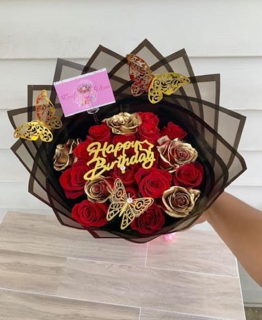 Bouquet of red and gold roses with butterfly decorations and a birthday sign