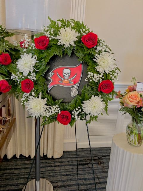 Floral wreath with red roses and white chrysanthemums around a sports logo