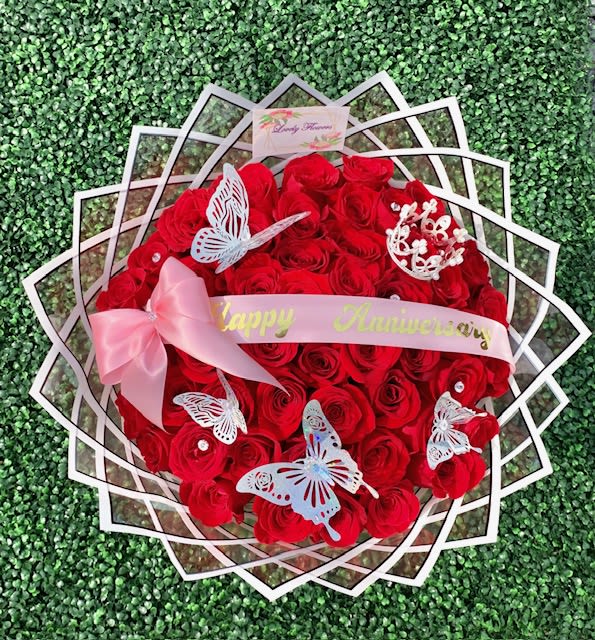 Round bouquet of red roses with pink ribbon and butterfly decorations