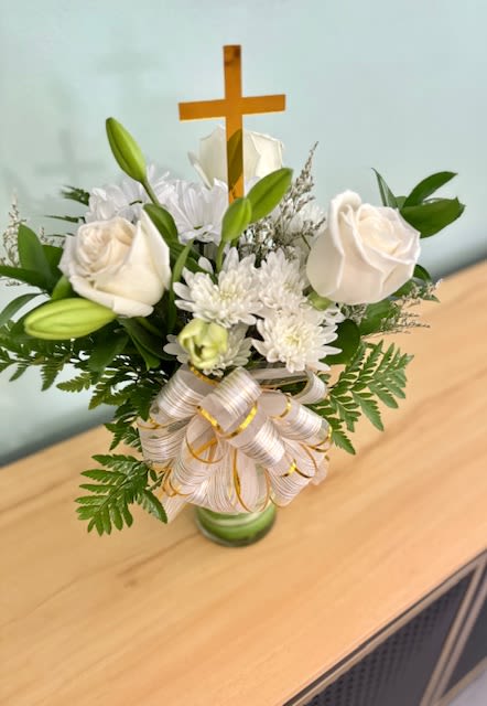 White roses and lilies arranged with a wooden cross