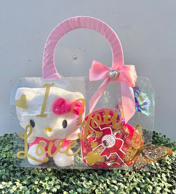 Kitty Kisses - A playful, romantic gift bag that just for them-perfect as a sweet anniversary or Moter Day surprise. This clear gift bag pairs a white Hello Kitty plush with bright red candy and metallic gold lettering that reads "I love you," so the person you're thinking of will see the message before they even open it.  The presentation mixes pink, white, and red tones with decorative butterfly accents for an extra touch of whimsy. A wide pink ribbon handle and a satin pink bow with a heart embellishment finish the look; included hard goods are the clear gift bag, Hello Kitty plush, candy assortment, and gold-lettered accents. The compact size and cheerful color palette make this an easy grab-and-go treat for someone who loves cute, themed gifts.  Ideal for a romantic token, a thoughtful pick-me-up, or a small celebration (birthday, Valentine, or "just because"), this gift bag gives an immediately joyful impression that will make the recipient feel seen and loved. Order with standard wrapping-ready to present as shown-and keep candies sealed until giving for best freshness.