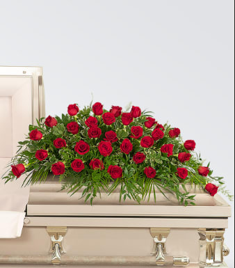 Forever love of Life Casket Spray - A dense spray of deep red roses laid across the top of a casket creates a solemn, respectful tribute for a funeral or memorial service. This casket spray for sympathy occasions centers on clustered red roses with abundant green foliage and fern-like accents, giving a traditional, dignified presence that honors the person you're remembering.  Crafted in a low, spreading form to rest gracefully on a beige casket, the arrangement combines rich red blooms with crisp white highlights and verdant greenery to soften the composition and add natural texture. Its formal silhouette and classic palette convey deep love and respect, making it an appropriate choice for family members or close friends who want to express heartfelt farewell.  We deliver and set this up at the funeral home and send you confirmation. 