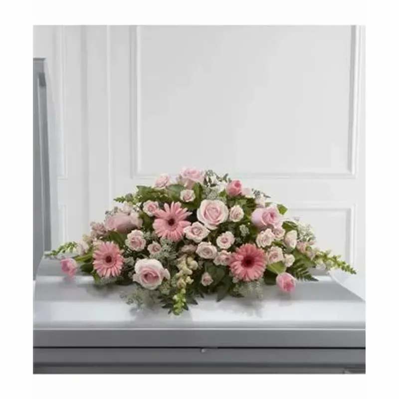 FTD Sweet Farewell™ Casket Spray - Blushing pink roses, gerbera daisies, spray roses, tulips and snapdragons are offset by a variety of lush greens and lovingly arranged to create a stunning accent piece intended to adorn the top of their casket at their memorial service. 