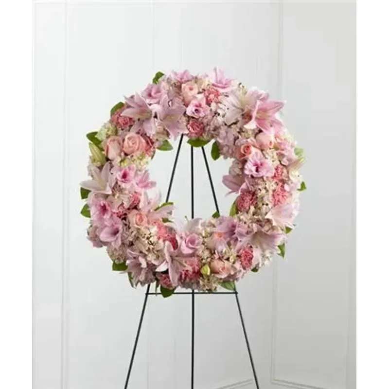 FTD Loving Remembrance™ Wreath - Pink roses, Oriental lilies, gladiolus, hydrangea and carnations are brought together with lush greens to form the shape of a wreath, offering warmth and comfort with its sweetly sophisticated elegance. Displayed on a wire easel. 