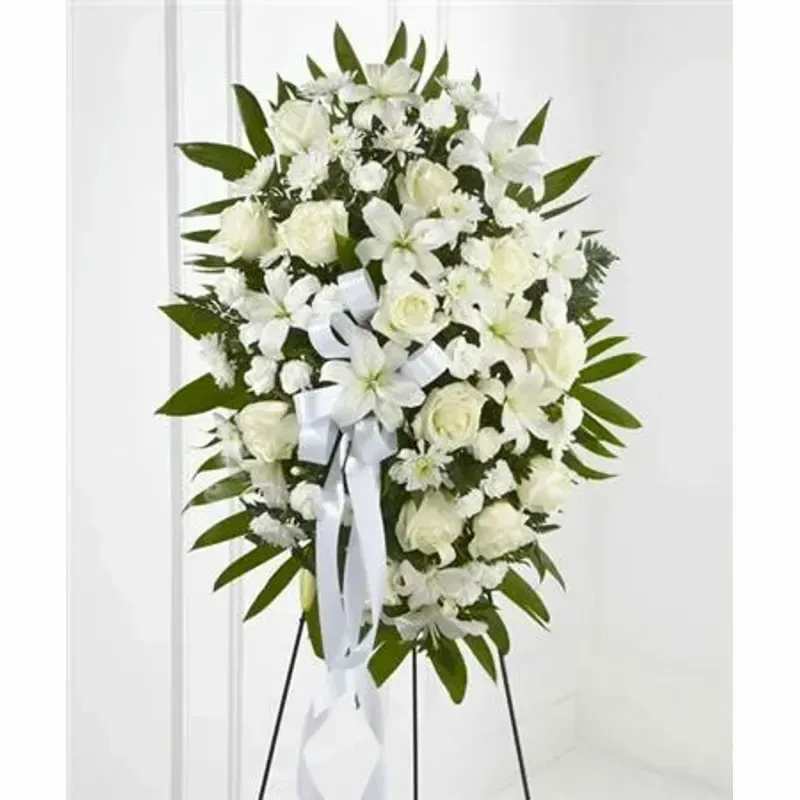 FTD Exquisite Tribute™ Standing Spray - White roses, Asiatic lilies, chrysanthemums and mini carnations are artfully arranged amongst emerald palm fronds and lush greens. Accented by white satin ribbon and standing on a wire easel, this standing spray is an outstanding way to honor the life of your loved one. 