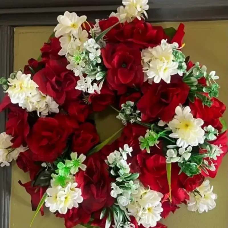 Memorial Wreaths x4 14" - A ring of deep red roses arranged in a classic 14" wreath makes a bold, reverent statement-ideal as a sympathy or funeral floral tribute that honors a life with timeless elegance. The red rose base conveys love and respect, while the small white daisy-like blooms threaded through the composition add bright contrast and a gentle, consoling note for the person you're remembering.  Densely packed and layered for a full, ceremonial presence, this circular arrangement blends rich crimson texture with crisp white accents and green foliage to outline the form. The compact 14" size is substantial enough to display on an easel or lay on a casket yet still easy to transport and position; the finished wreath form gives a polished, formal look suitable for memorial services or placing at a graveside.  Whether chosen to express sympathy after a recent loss or to mark an anniversary of remembrance, this wreath communicates heartfelt respect and lasting remembrance. Care is simple-keep the foam moist until service and avoid prolonged exposure to direct heat-to maintain the roses' rich color and the daisies' fresh contrast until the tribute is complete.