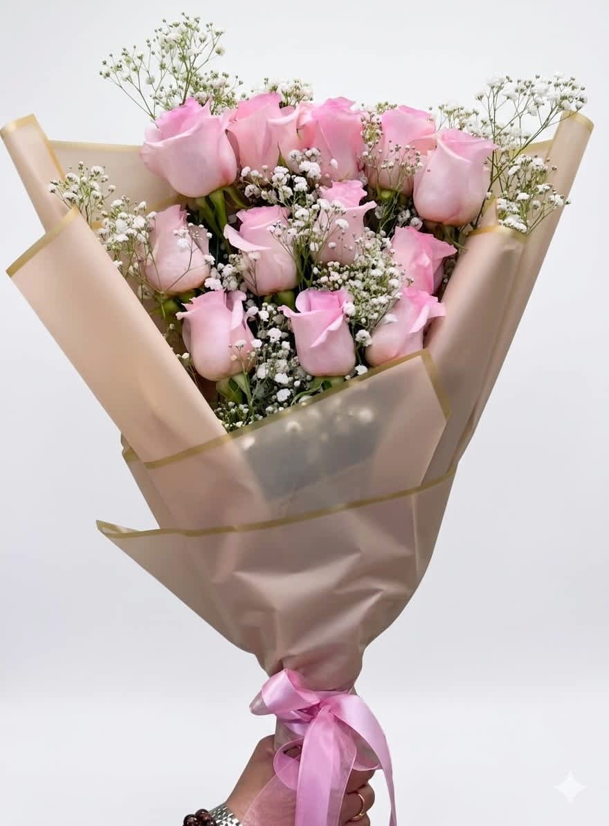 Soft Blush by The Flower Spot™ - A compact cluster of bright pink roses makes an immediate, romantic impression-perfect as a birthday bouquet, anniversary roses, or a just-because arrangement to make someone feel truly cherished. The Soft Blush by The Flower Spot™ presents those rosy blooms in a rounded hand-tied shape so the recipient sees the lush color and texture up close; the soft, feminine palette of pink, white, and green reads intimate and celebratory rather than overblown.  Each rose is carefully curated and framed with airy filler greens that add lightness and contrast, then wrapped in cream decorative paper with a soft pink edge for a polished, gift-ready presentation. A satin ribbon at the base completes the luxury feel and keeps the bouquet compact-easy to carry and display. This arrangement is sized for personal gifting and arrives ready to place in a vase; to keep the roses fresh, recut stems and change the water daily for best longevity.