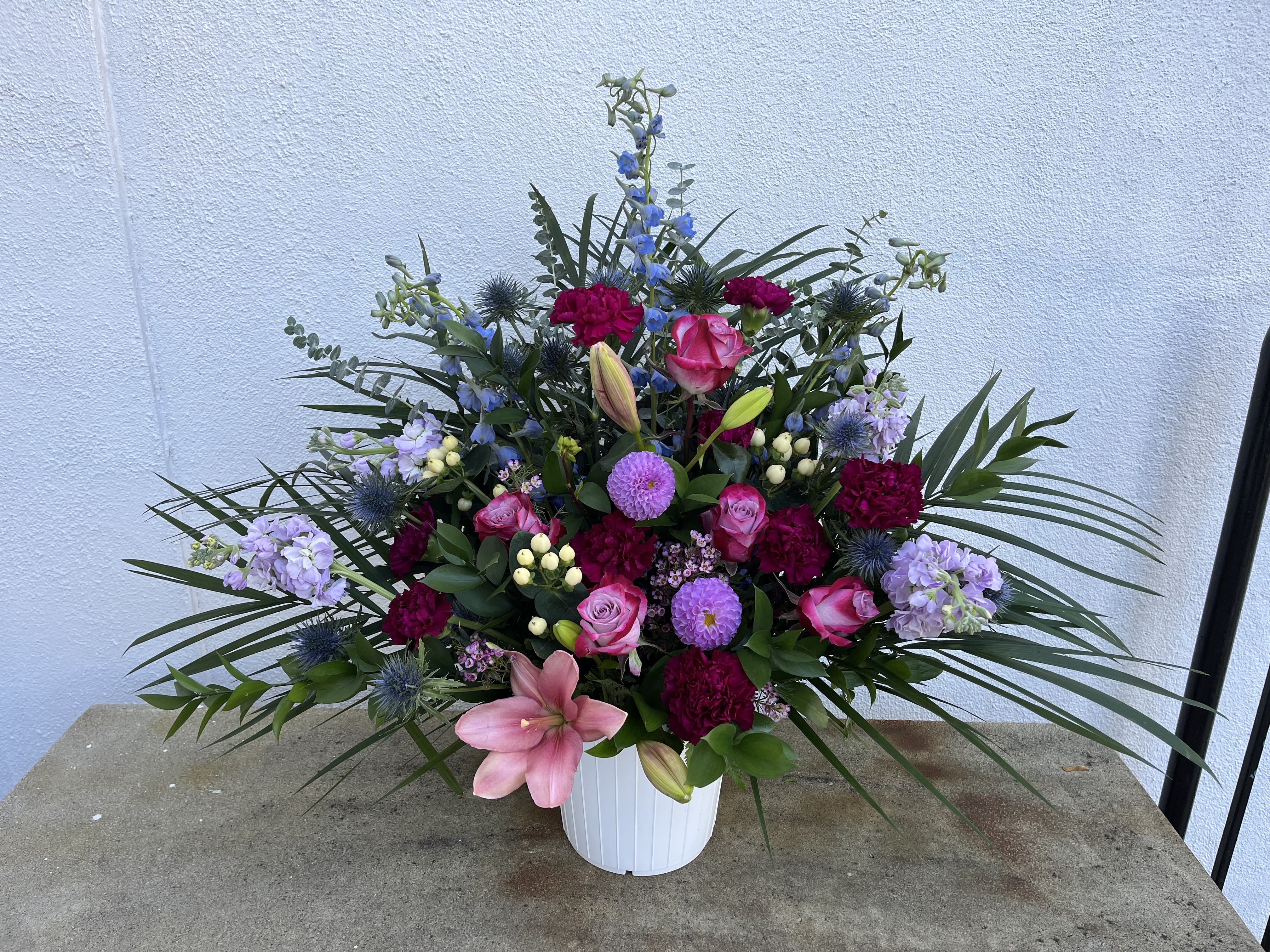 Mixed pink, purple, and blue floral arrangement in a white vase