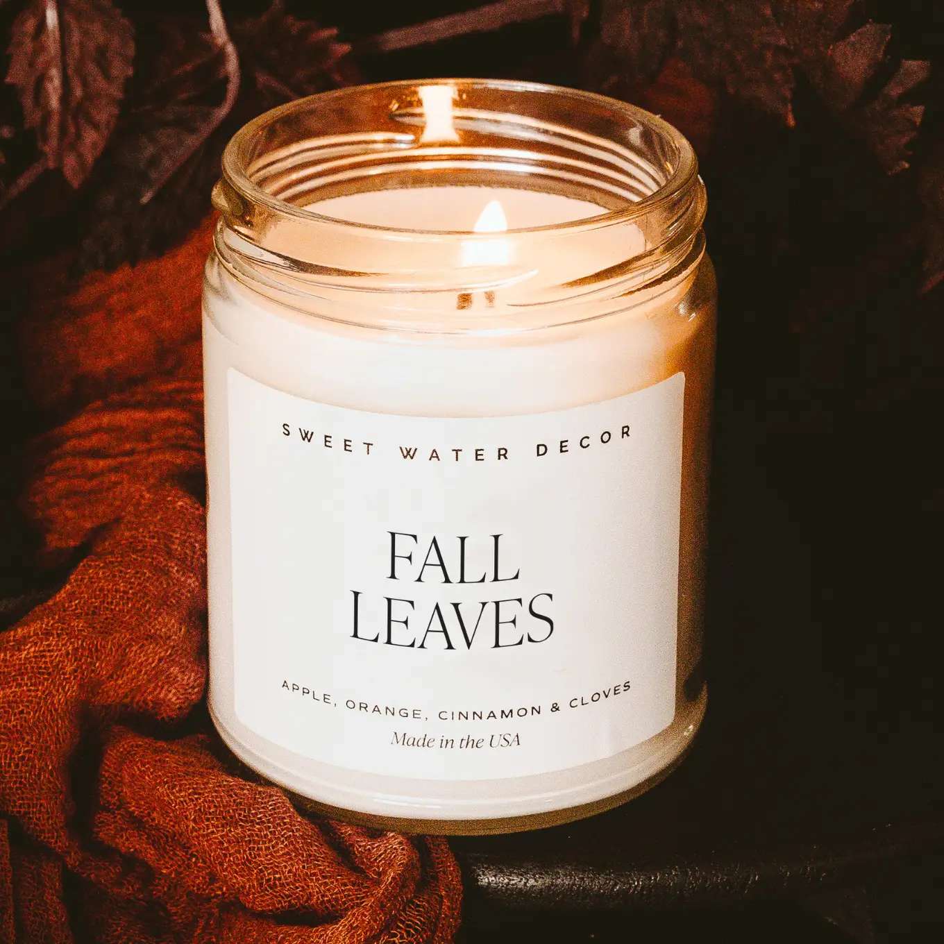 Lit candle in a glass jar labeled Fall Leaves