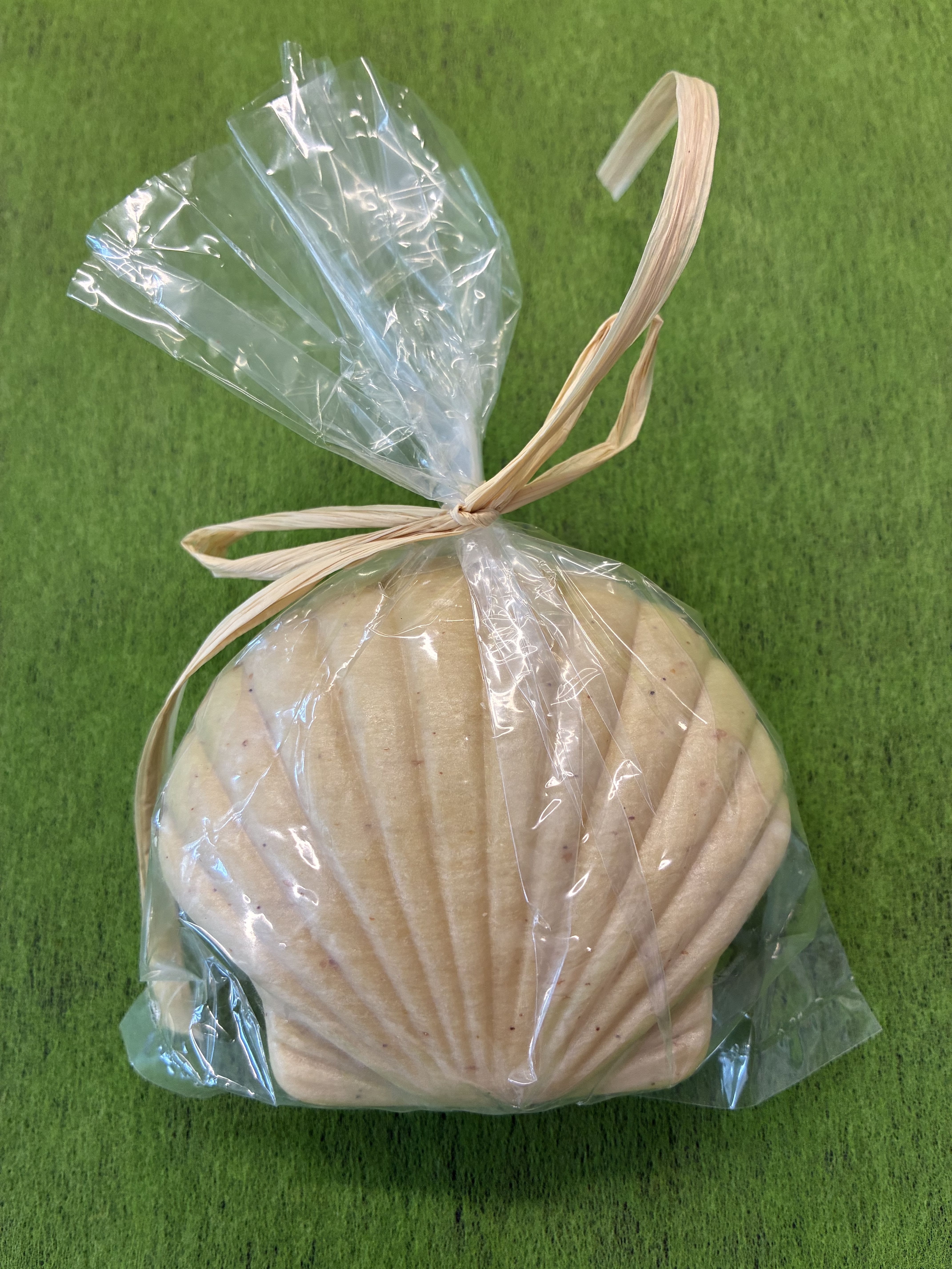 Shell soap - A coastal-inspired decorative soap shaped like a shell makes an effortless "just because" gift that feels thoughtful and serene. Perfect for housewarming, thank-you, or thinking-of-you moments, this wrapped shell soap brings a touch of seaside charm to any bathroom or guest powder room and reads fresh for spring and summer gifting.  The soap arrives nestled in clear plastic wrap and finished with a rustic raffia tie, the shell's ribbed, matte beige surface catching light with a soft, natural texture. Its compact size and understated look make it an easy add-on for gift sets or a standalone accent on a vanity or bedside tray.  Give to someone recovering at home as a small get-well pick-me-up, tuck into a hostess basket for a housewarming, or include with a bouquet as a thoughtful finishing touch. Simple care: keep dry between uses to preserve the matte finish; packaged ready to present, it's an instant, gracious gift.