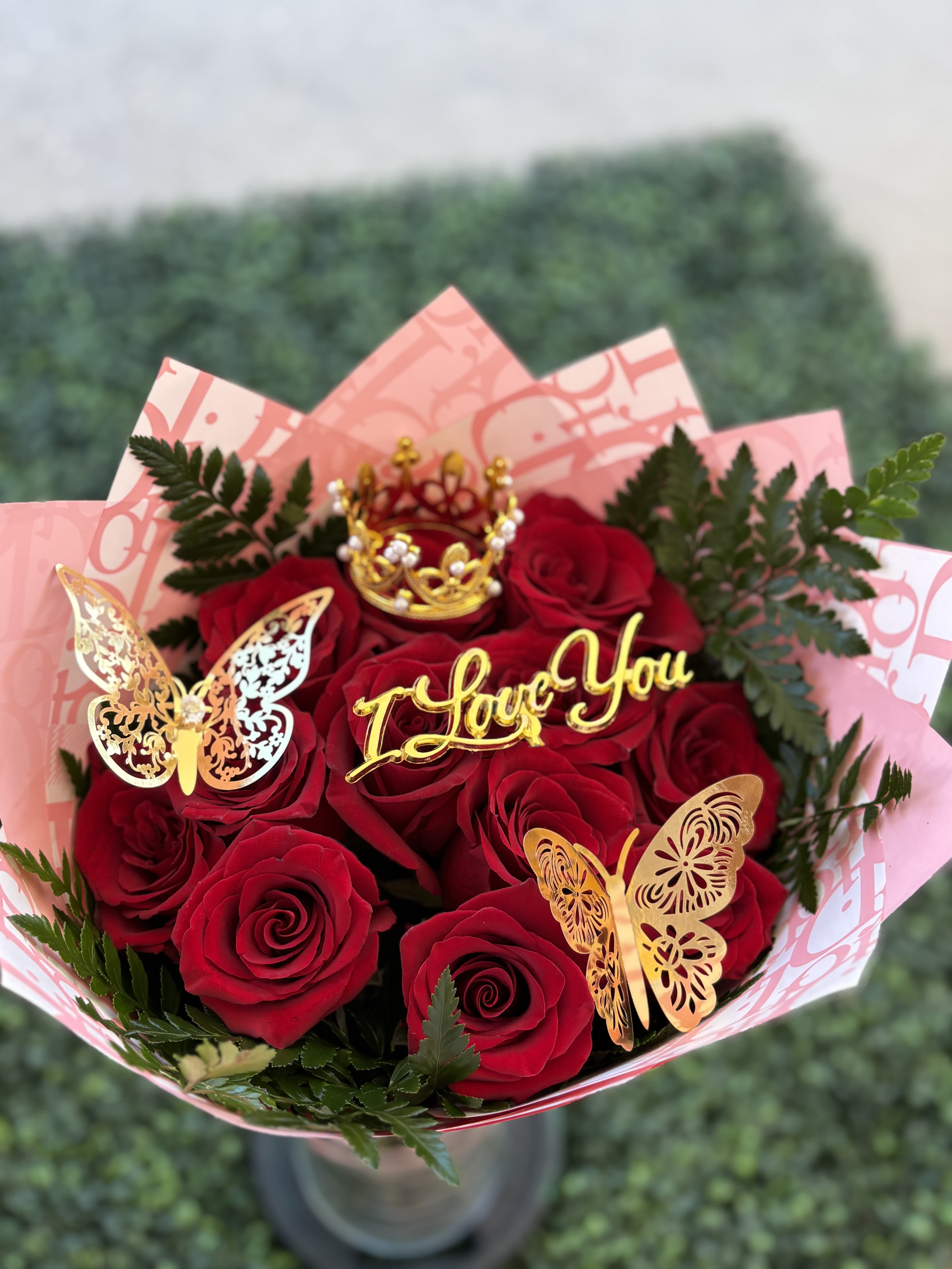 Bouquet of red roses with gold butterfly decorations and a "I Love You" topper
