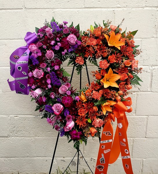 Heart-shaped floral wreath with purple, pink, and orange flowers on a stand