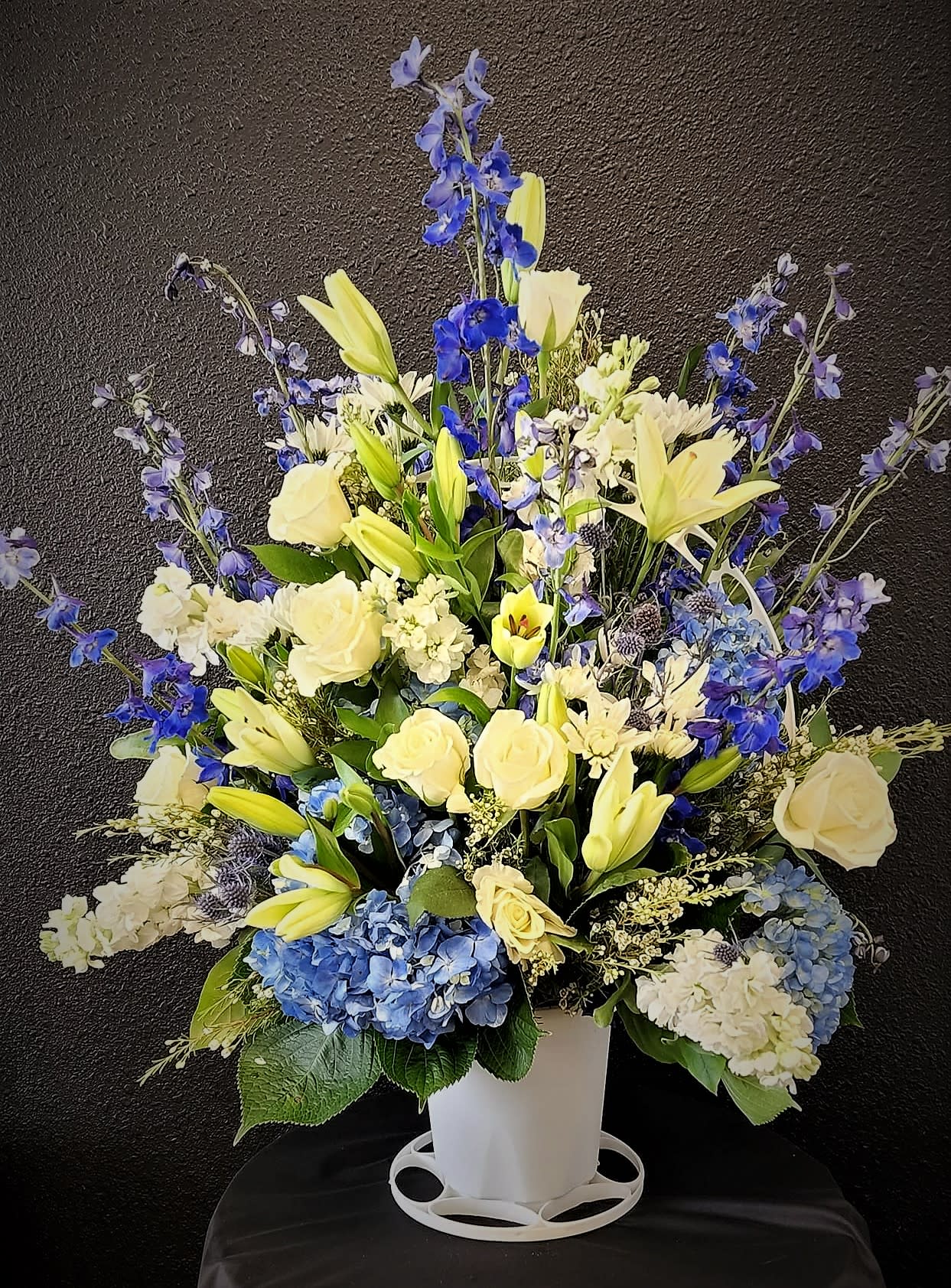 Tall blue and yellow floral arrangement in a white vase