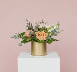 Peach and pink rose arrangement in a gold cylinder vase