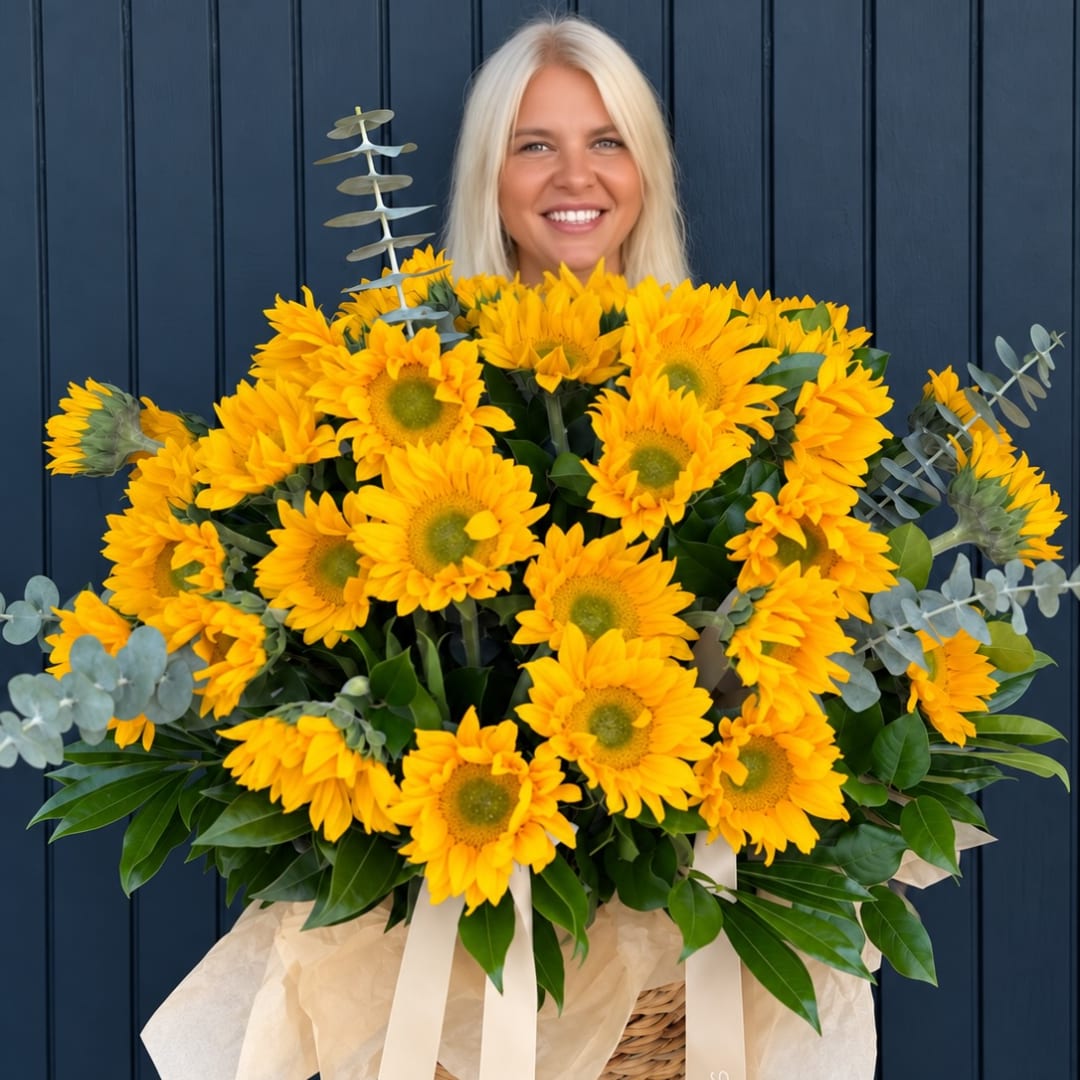 Large bouquet of yellow sunflowers with eucalyptus and ribbon in a basket