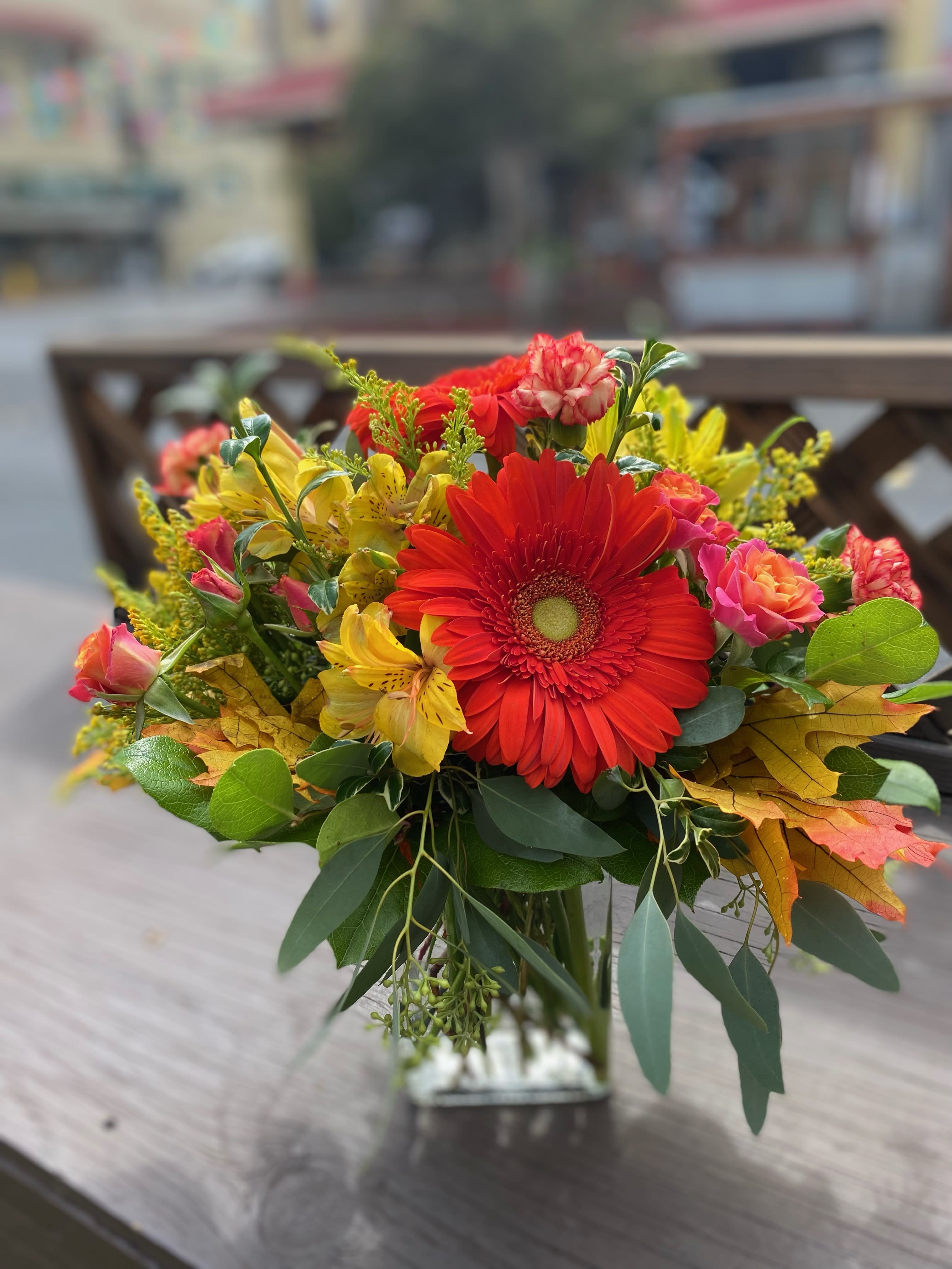 Bouquet of red gerbera daisies and yellow flowers in a glass vase