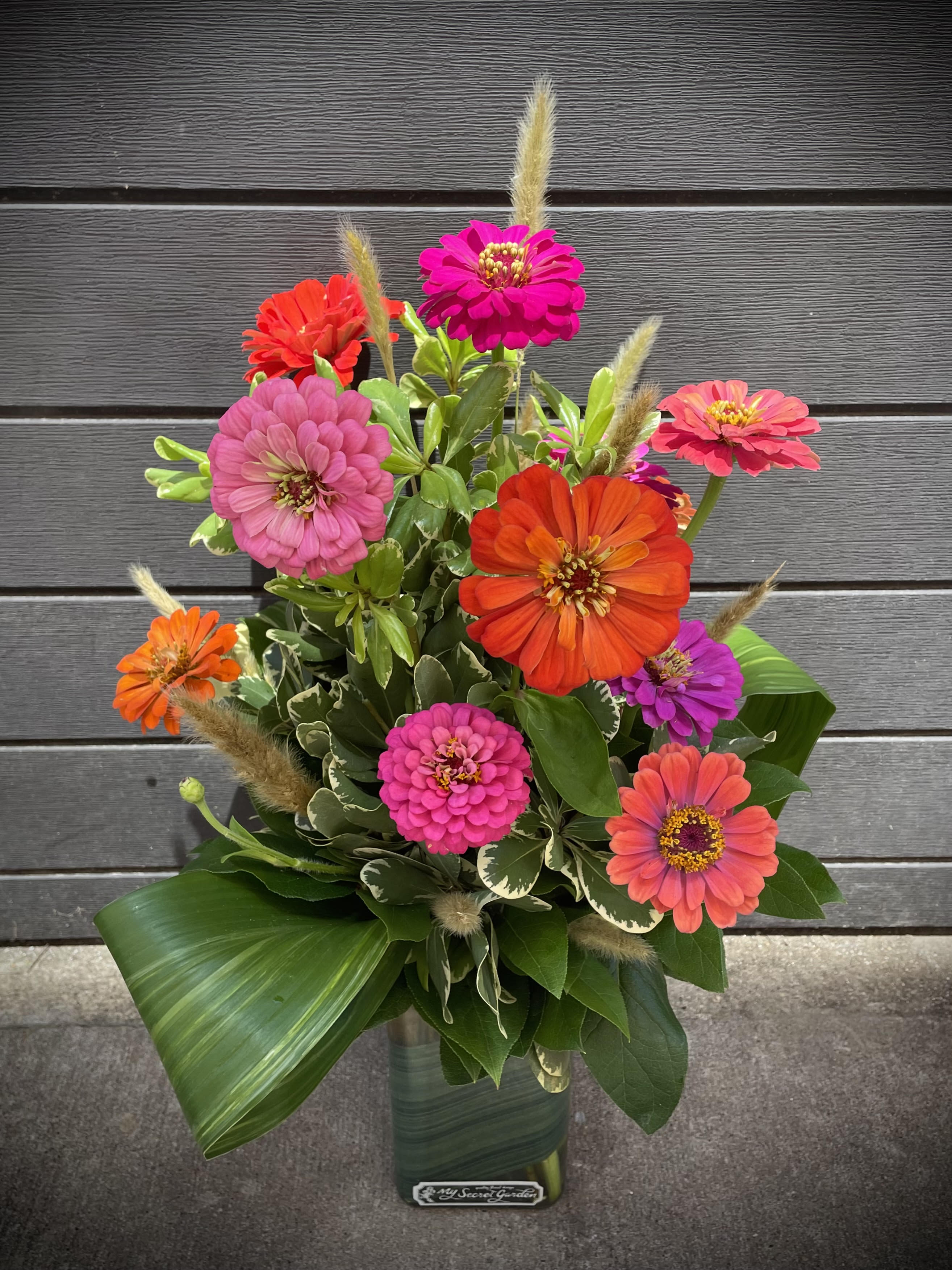 Bright zinnia bouquet in a glass vase with mixed pink, orange, and purple blooms