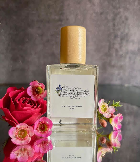 Perfume bottle beside a red rose and small pink flowers