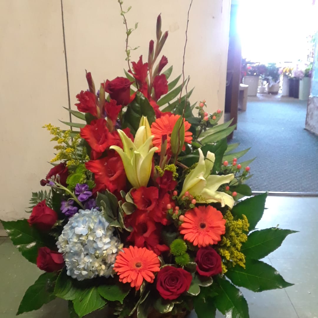 Mixed bouquet with red roses, orange gerberas, lilies, and blue hydrangea