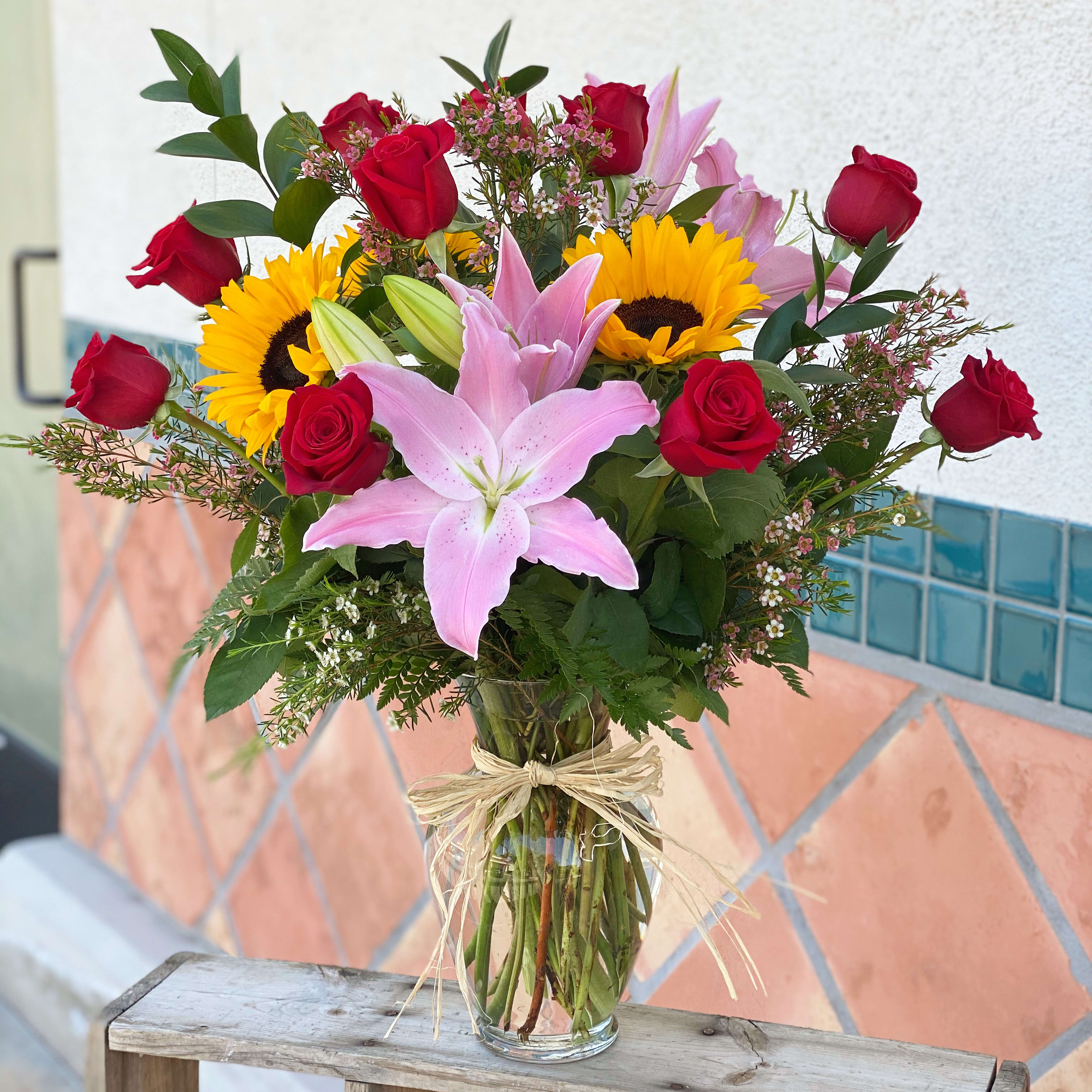 Happily in love bouquet  - A dozen red roses to tell her you love her.  Sunflowers are "happy" flowers, making them the perfect gift to bring joy to someone's day.  Pink lilies stands for love, administration, compassion, femininity, and understanding.  This bouquet is just perfect to show your love and care to the receiver. 