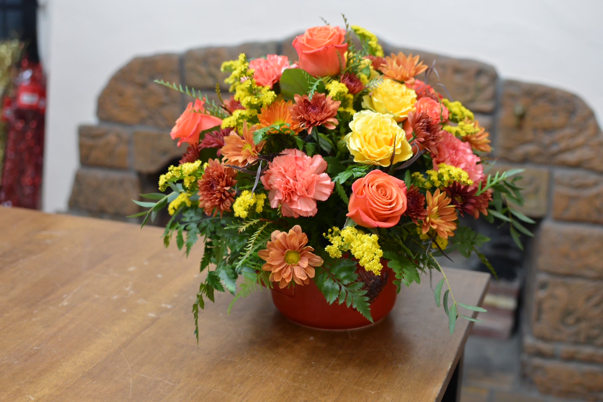 Pinecone harvests glow - Pinecone harvest glow features a rich blend of fall toned roses, carnations, and poms arranged beautifully inside a deep red container accented with a rustic pine cone. 