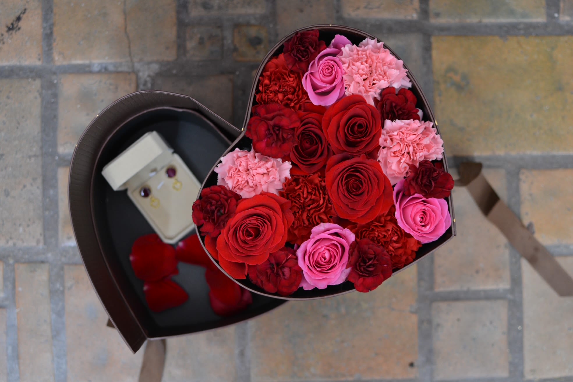 Bloom, Then Shine - A two-tier heart box featuring lush red and pink roses and carnations, with a hidden drawer revealing delicate earrings using pressed rose petal—because love should bloom beautifully and shine unexpectedly.  Round Gold-Plated Rose Petal Heart Earrings Delicate and timeless, these round gold-plated earrings feature a petite heart charm cradling a real preserved rose petal at the center. Each petal is carefully selected and sealed, making every pair truly one of a kind—no two are ever exactly alike.  Lightweight and effortlessly wearable, these earrings capture the beauty of love in its most natural form: imperfect, fleeting, and deeply meaningful. Designed to be worn daily or gifted as a keepsake for someone special.  Details: Gold-plated round setting - 12mm Heart charm detail Real preserved rose petal One-of-a-kind pair Handmade with care