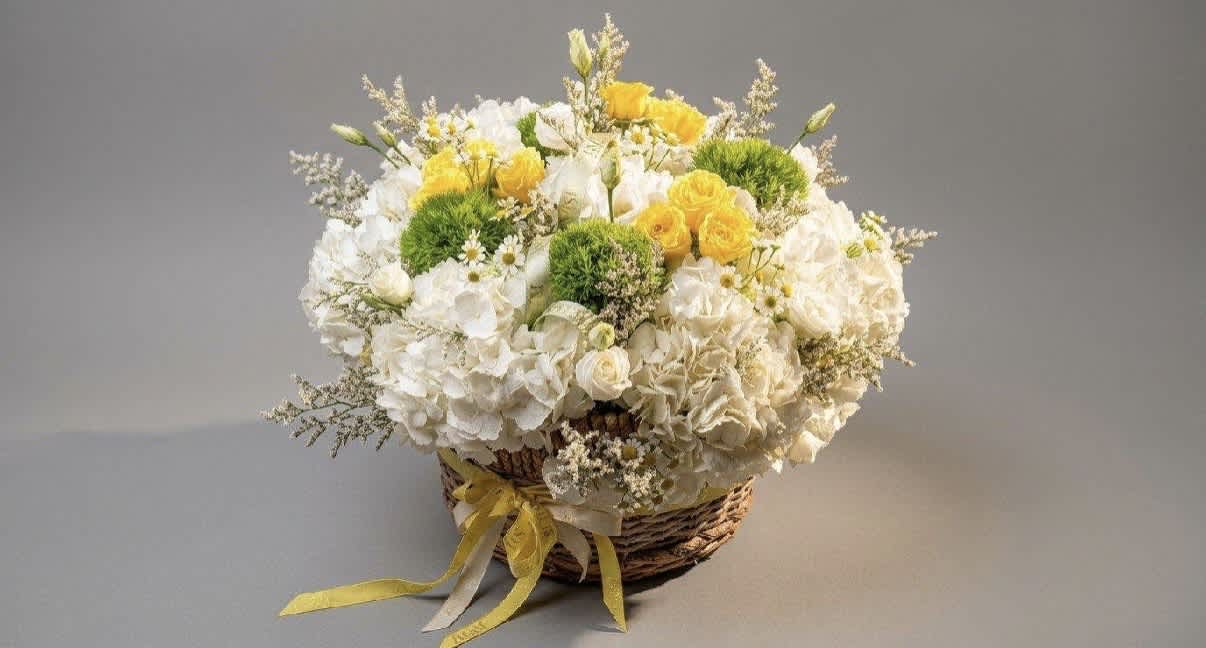 Basket arrangement of white and yellow flowers with green accents