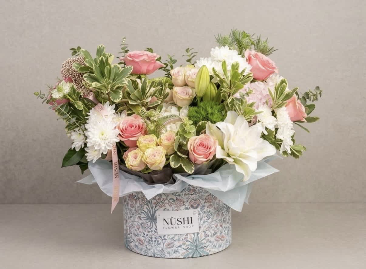 Pink and white flower arrangement in a patterned box