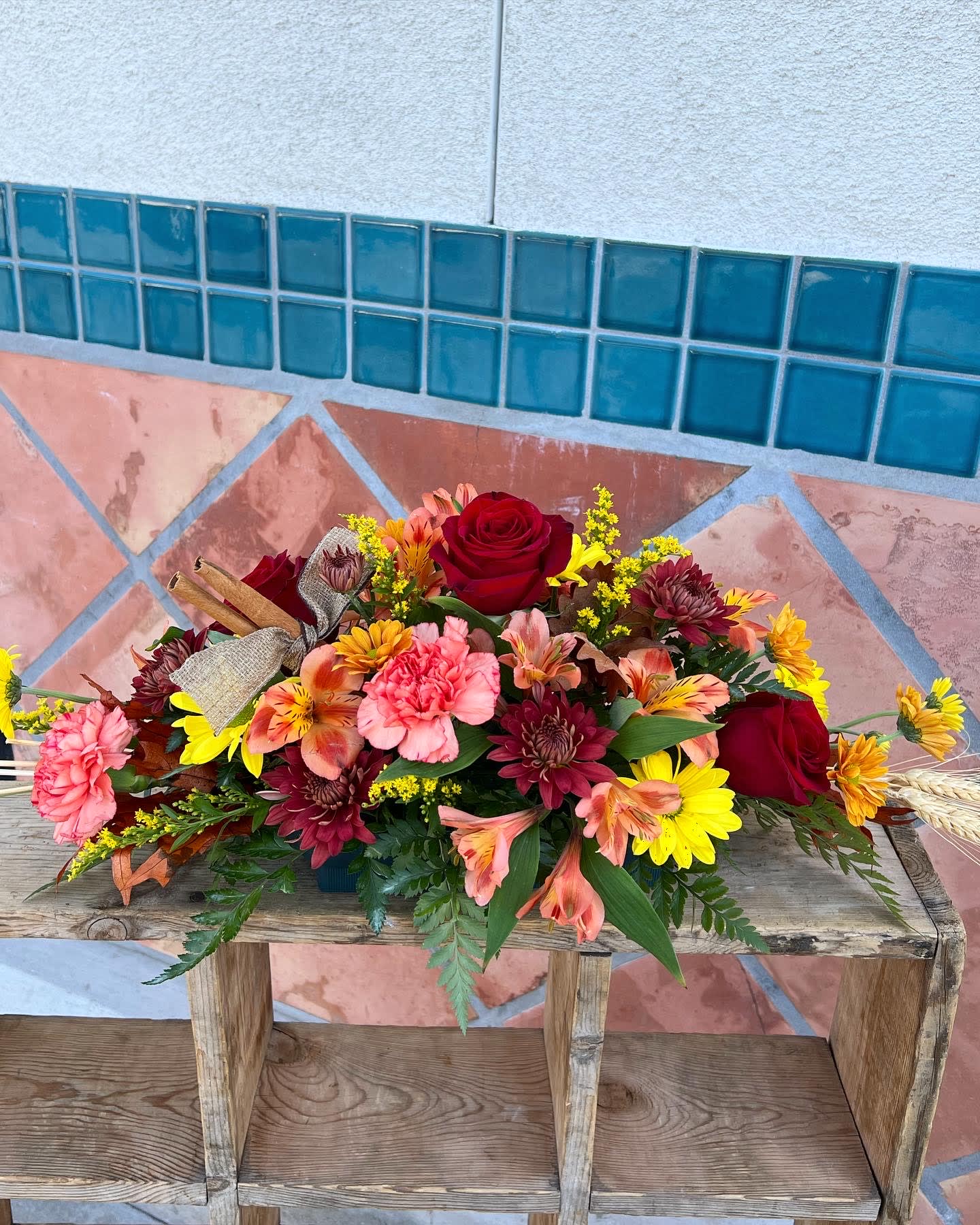 Mixed bouquet of roses, carnations, and daisies on a wooden bench