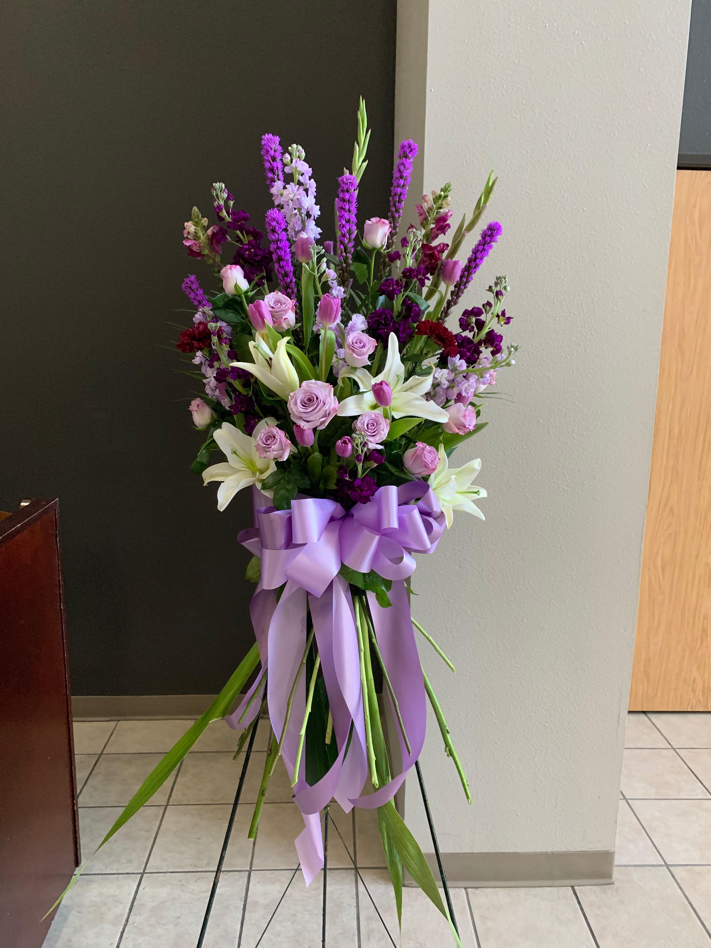Tall bouquet of pink and purple flowers with white lilies and a lavender ribbon