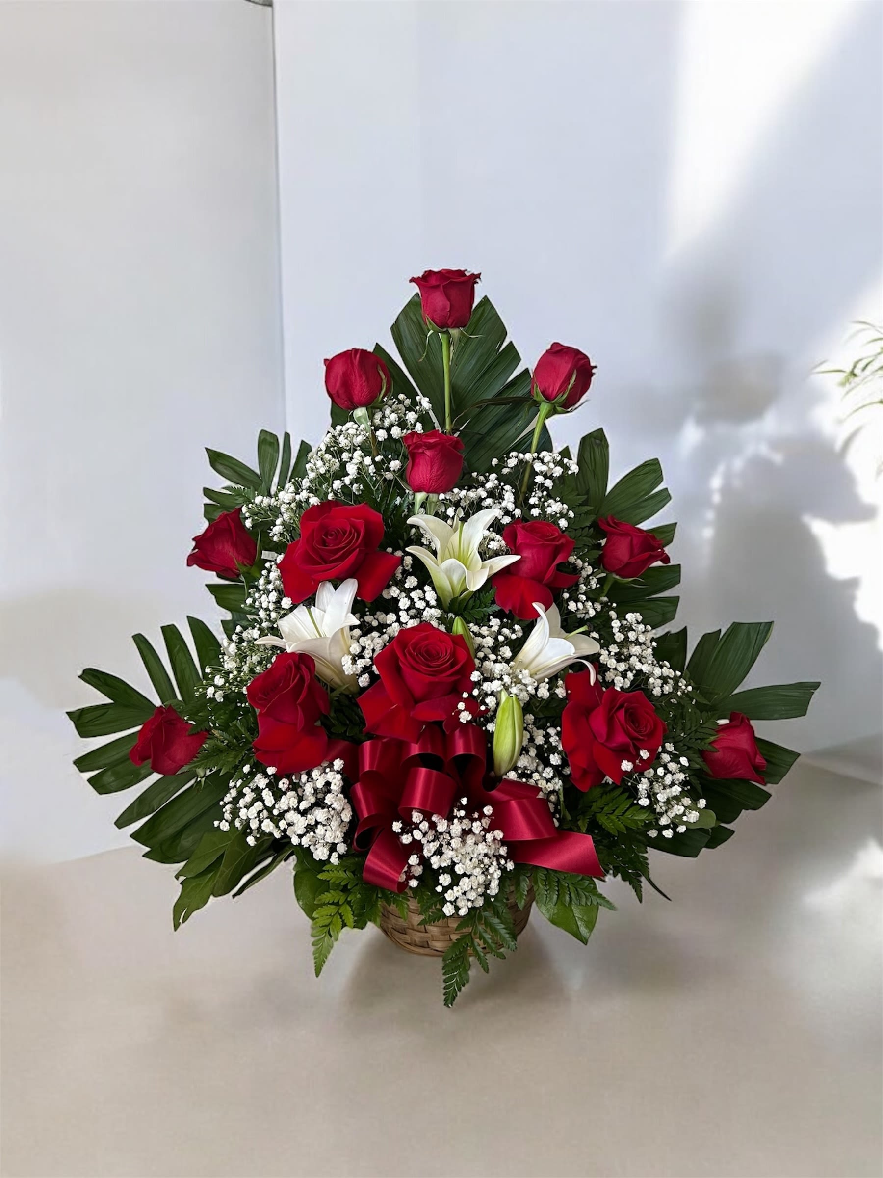 Red roses and white lilies in a basket with baby's breath