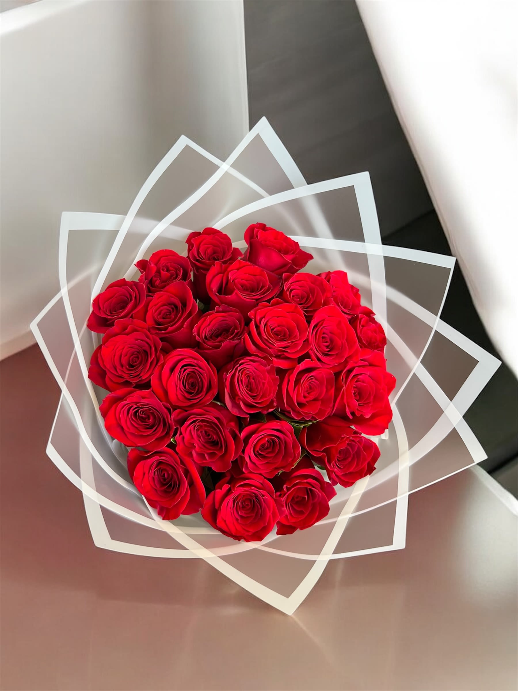 Bouquet of red roses wrapped in clear geometric paper