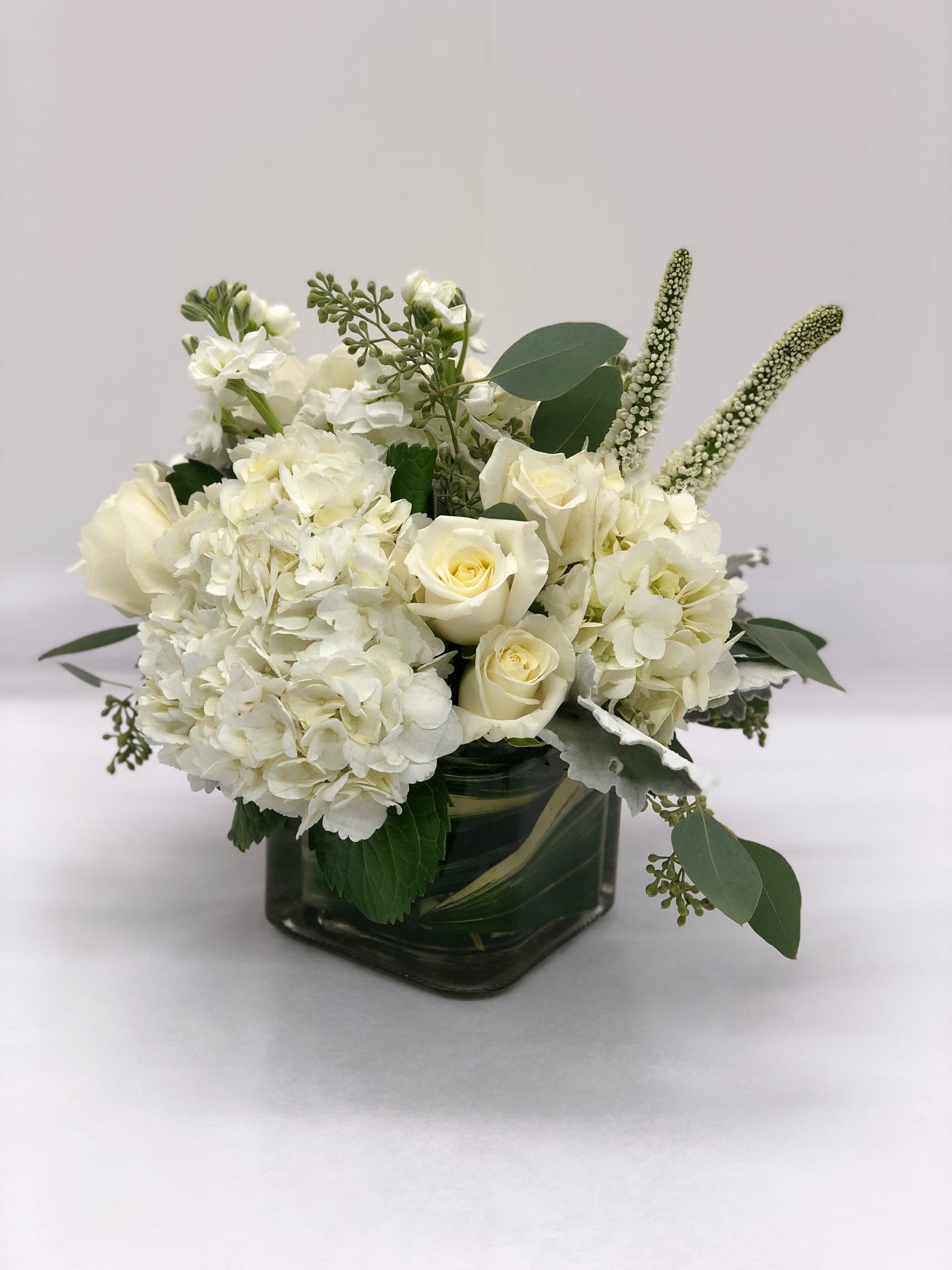 White roses and hydrangeas in a square glass vase