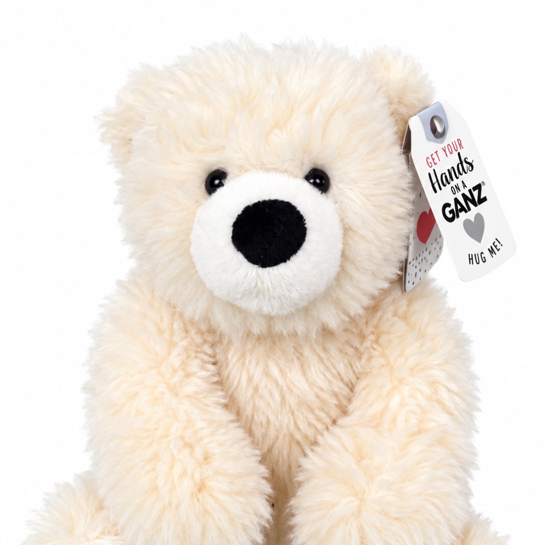 Cream-colored teddy bear with a tag on a white background