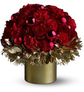 Teleflora's Golden Holly-Day - As pretty as a picture in a glossy magazine, this mix of vivid red blossoms and Christmas ornaments - resting on a bed of golden holly and evergreens, and presented in a golden Teleflora Satin Collection container - will bring a touch of glamour to any holiday gathering.  A mix of red and burgundy roses and carnations – arranged with shiny and matte red ornament balls – is presented with gold-sprayed holly and evergreens in a gold-colored Teleflora Satin Collection Cylinder.  Approximately 17" (W) x 17" (H)  Orientation: All-Around  As Shown : 08N930B