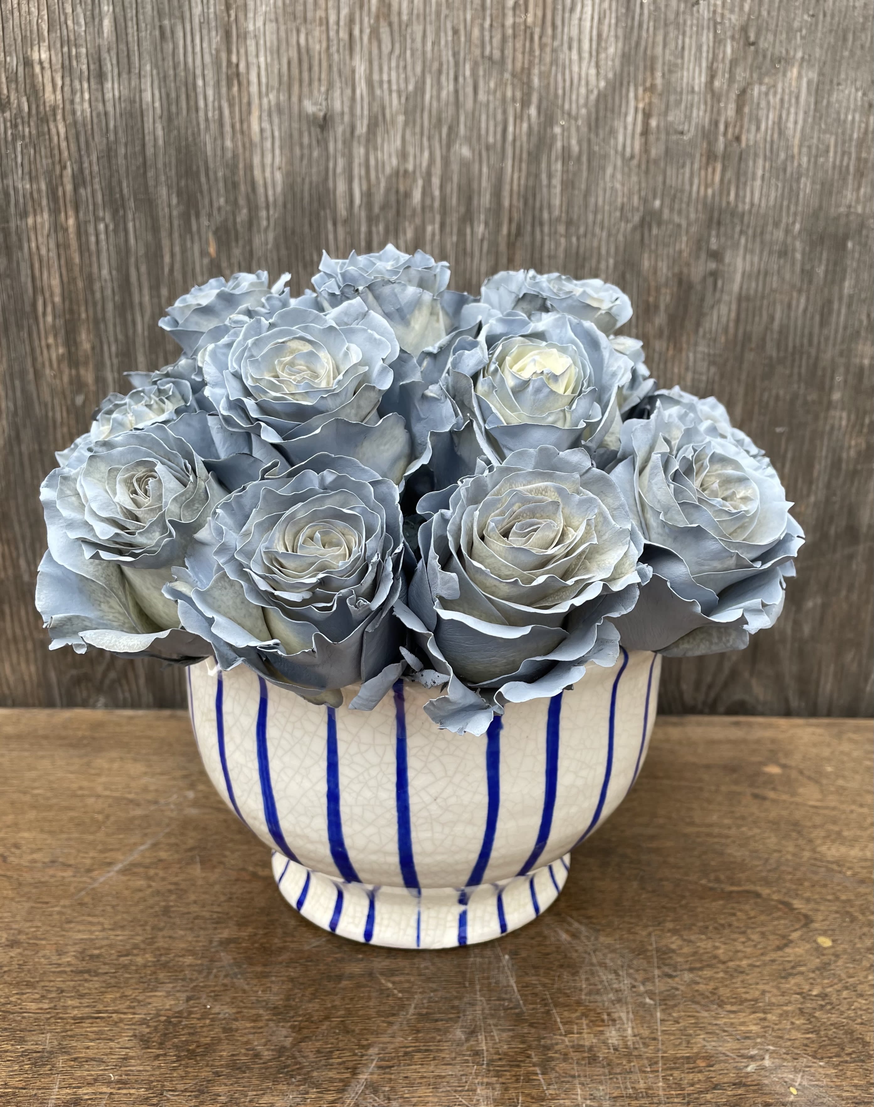 Blue-gray roses arranged in a striped ceramic vase