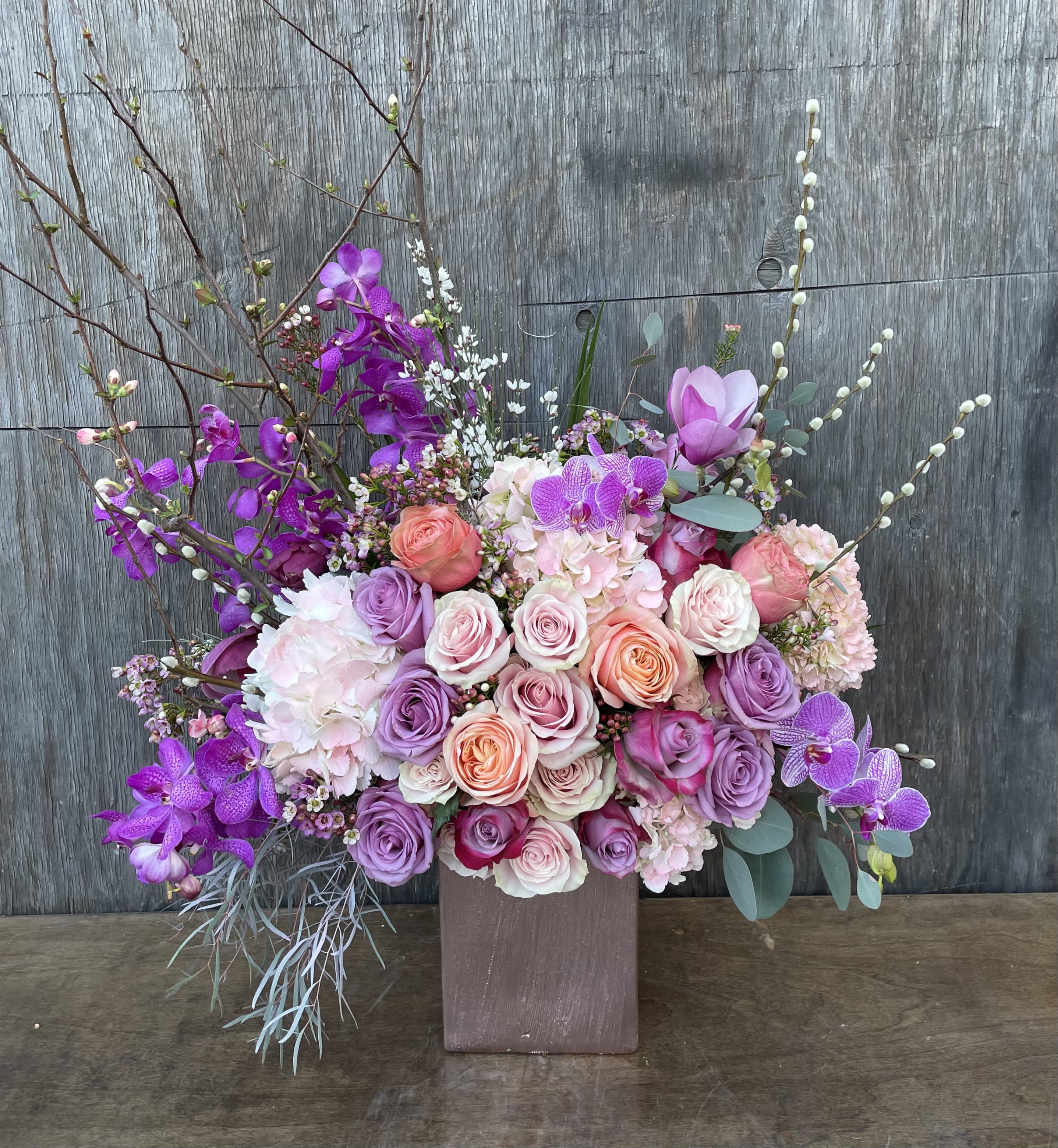 Large bouquet of pink and purple roses with orchids in a square vase