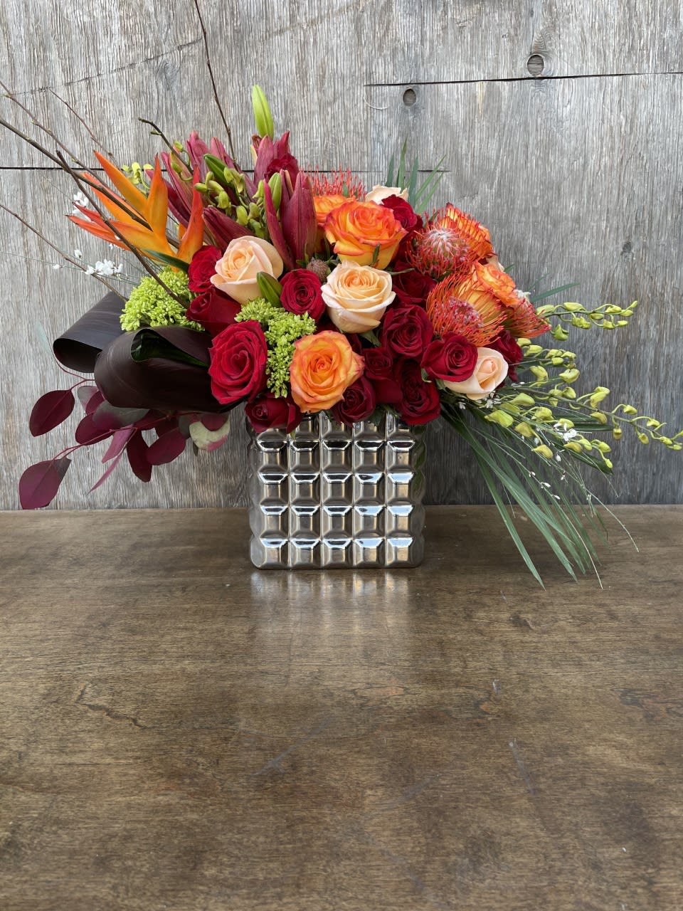 Mixed bouquet of red and orange roses in a silver vase