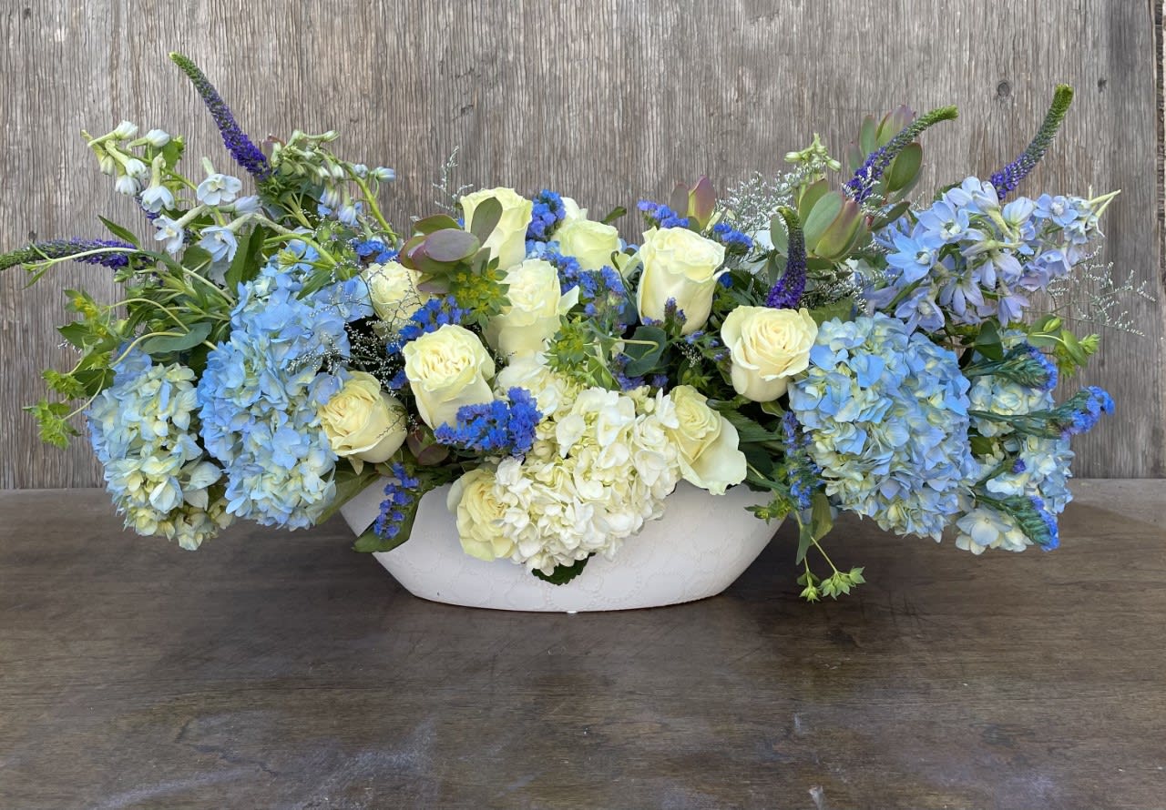 Blue and white floral arrangement in a white bowl vase