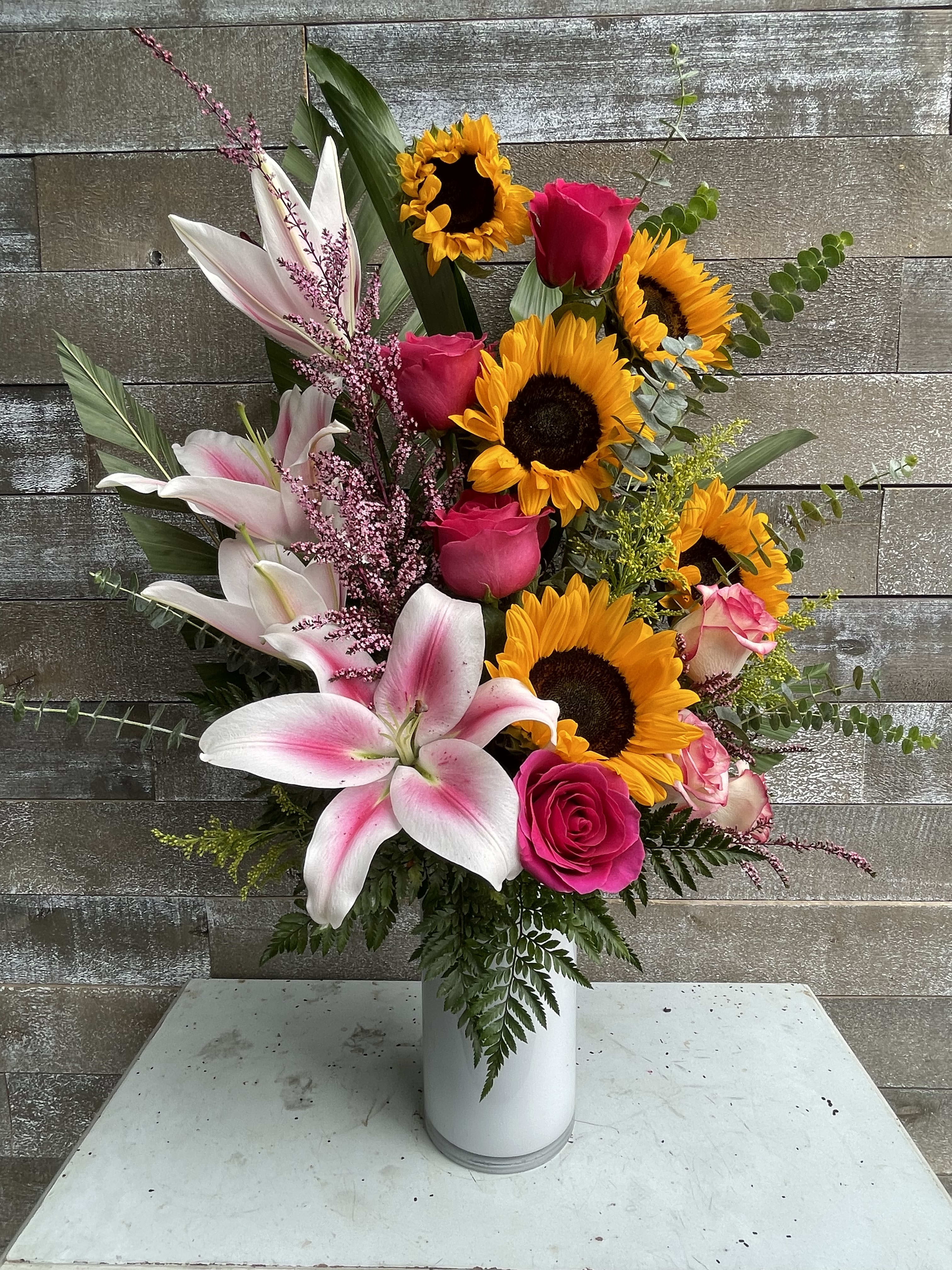 Pink roses and lilies with sunflowers in a white vase