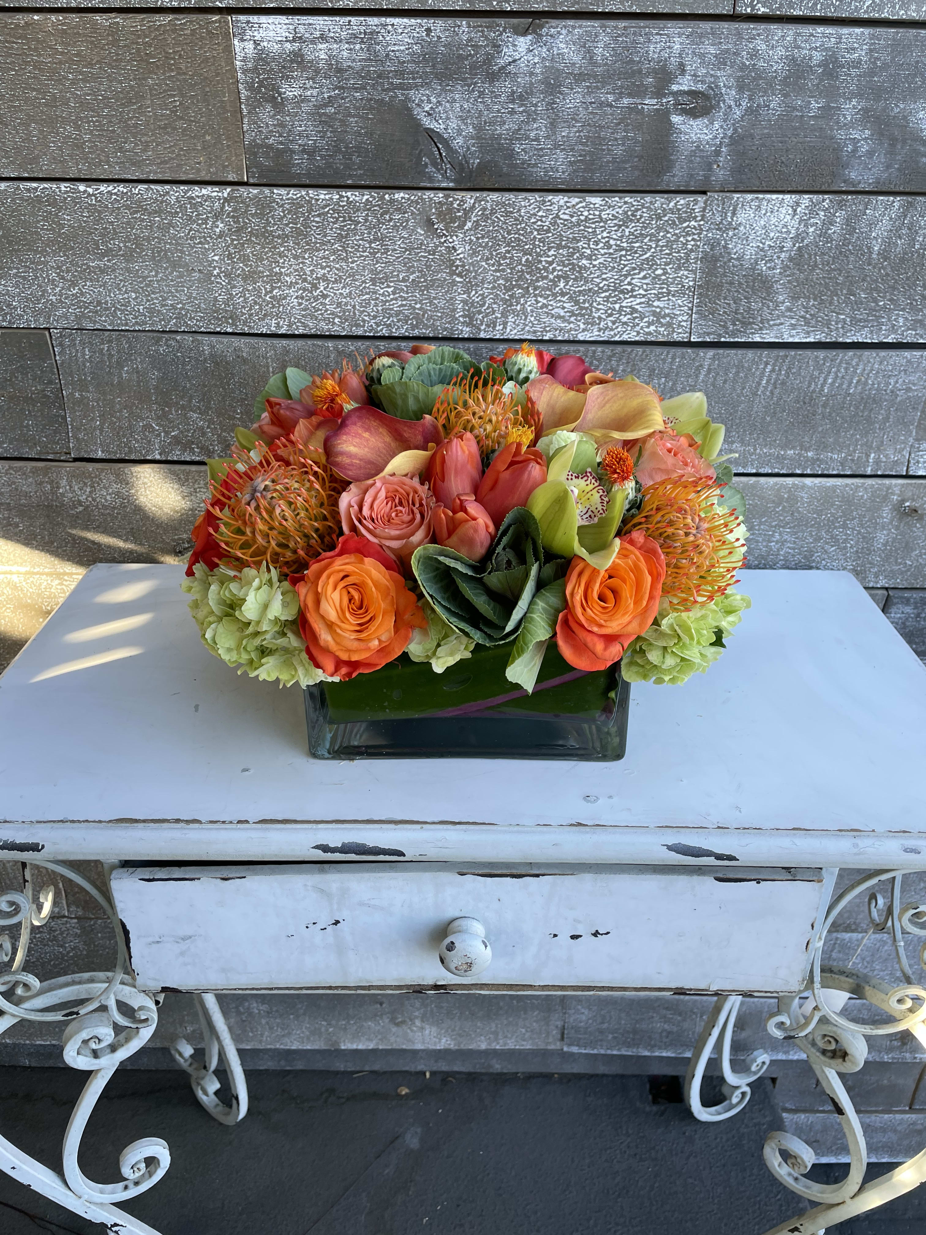 Bright mixed bouquet in a square glass vase