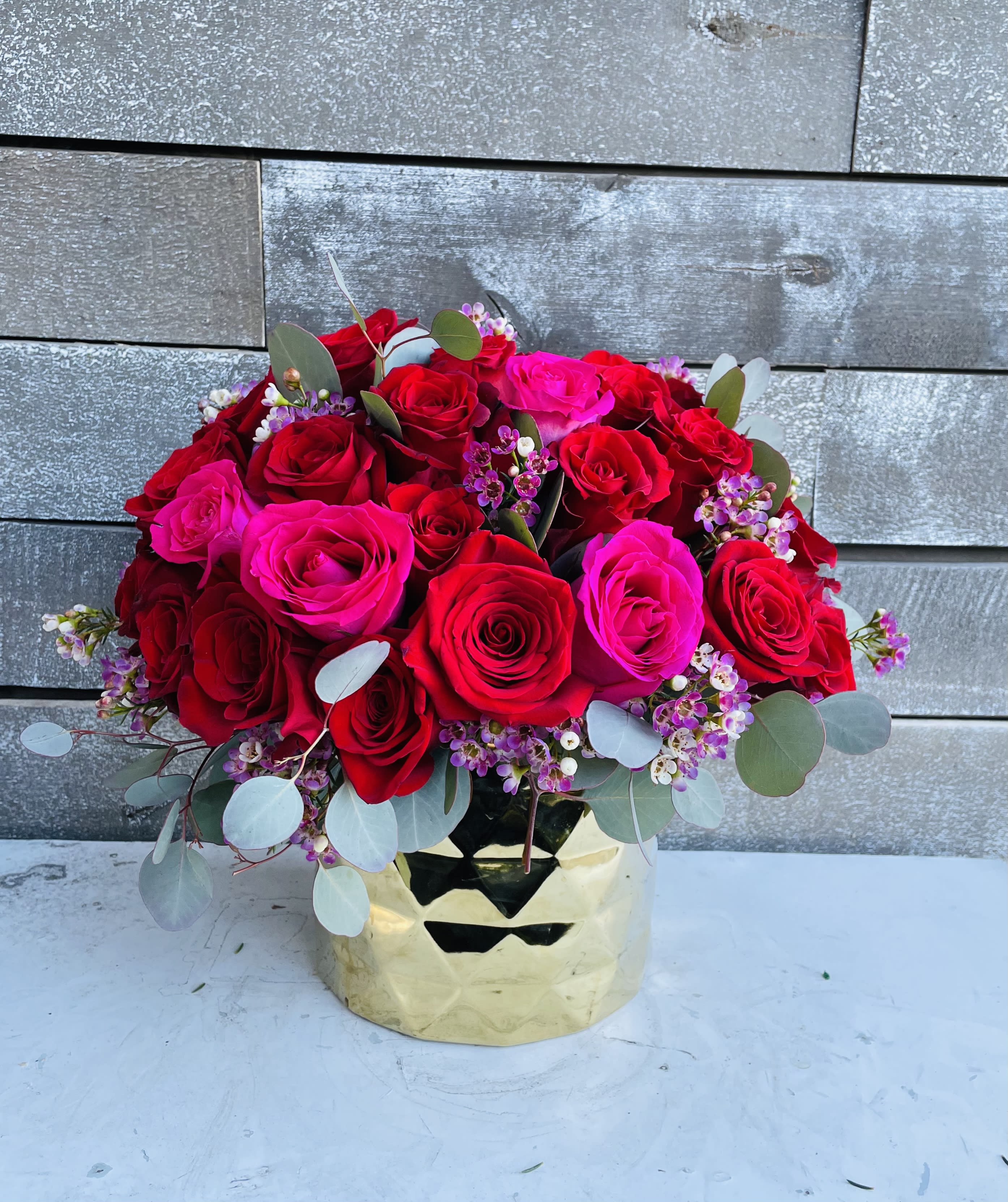 Bouquet of red and hot pink roses in a gold vase