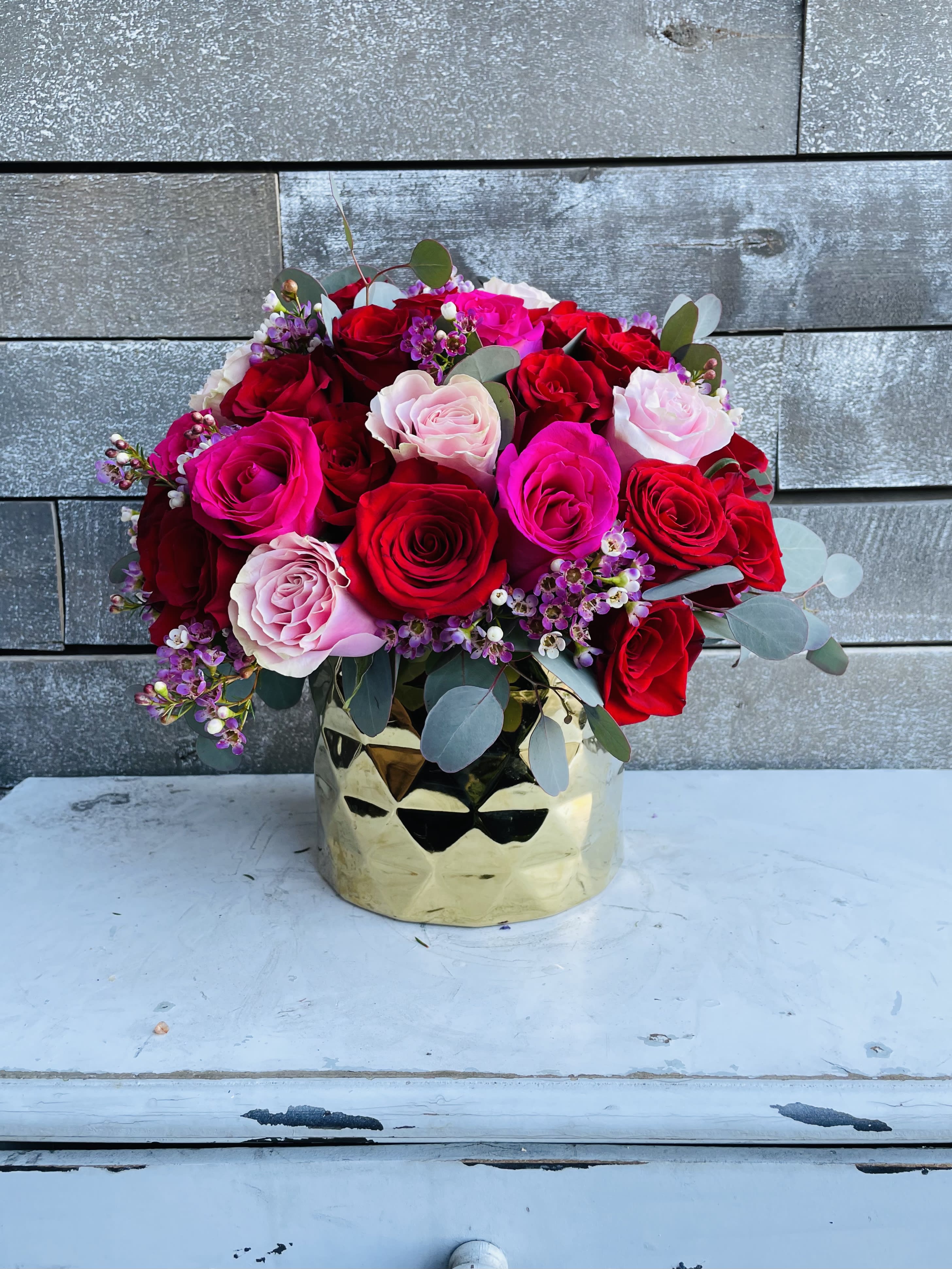 Bouquet of red, pink, and white roses in a gold vase