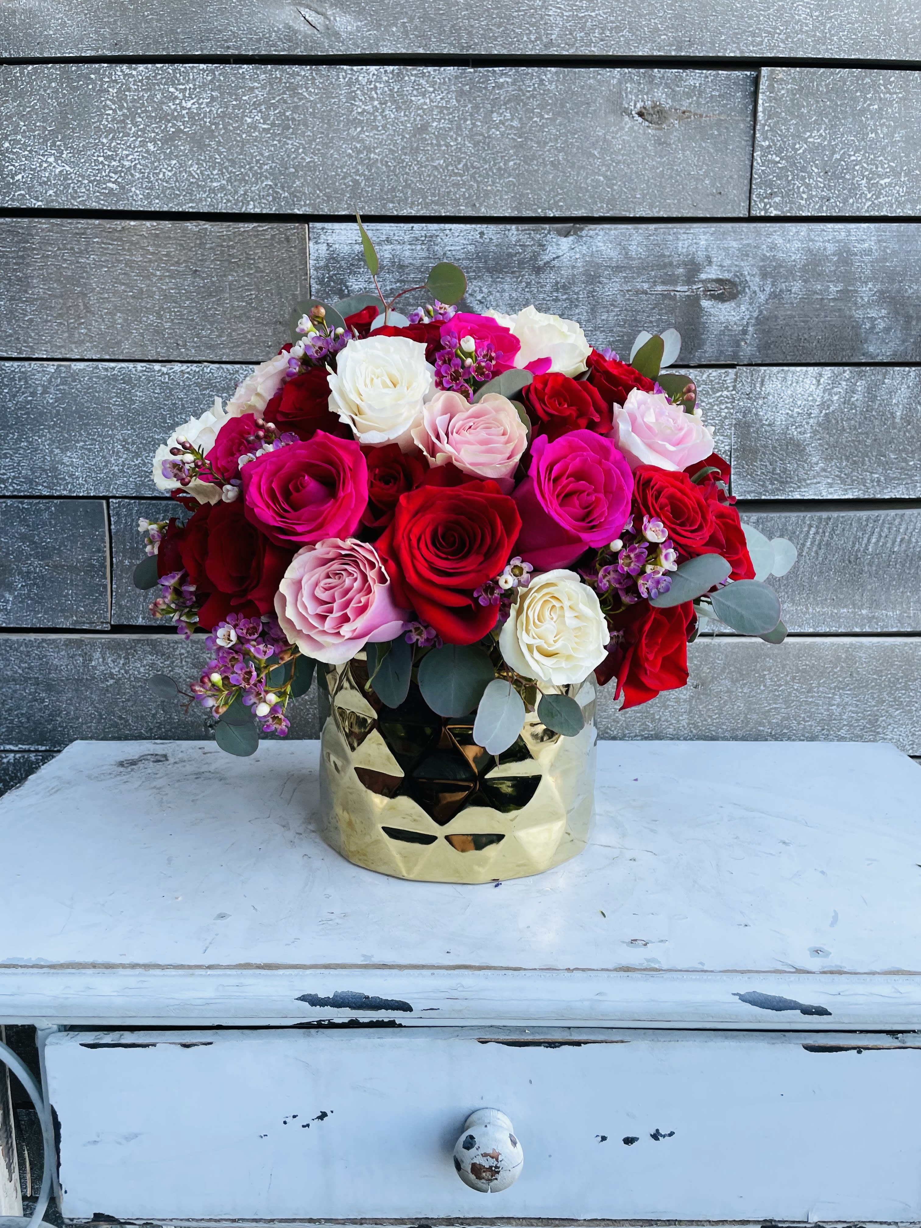 Bouquet of red, pink, and white roses in a gold vase