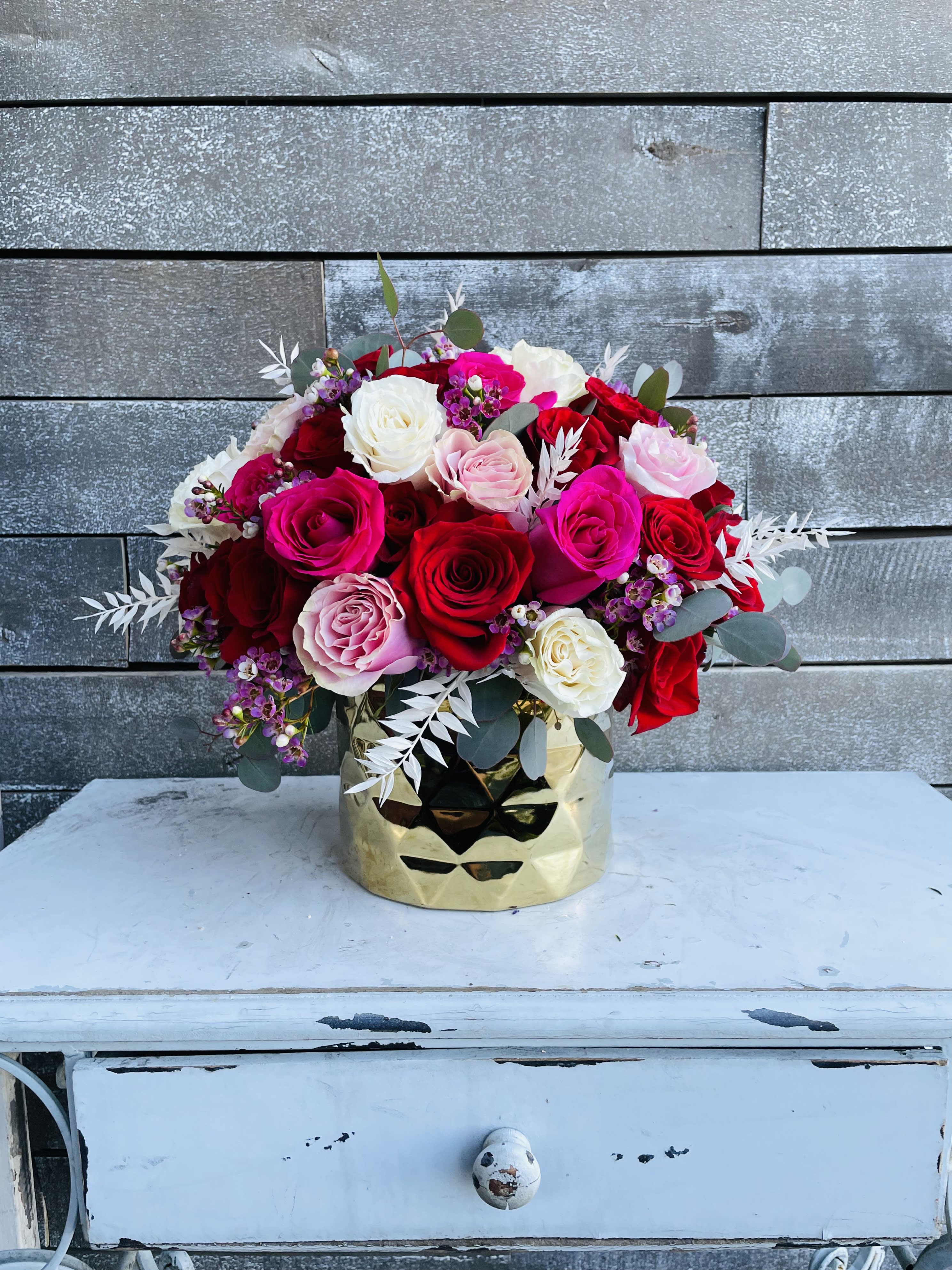 Bouquet of red, pink, and white roses in a gold vase