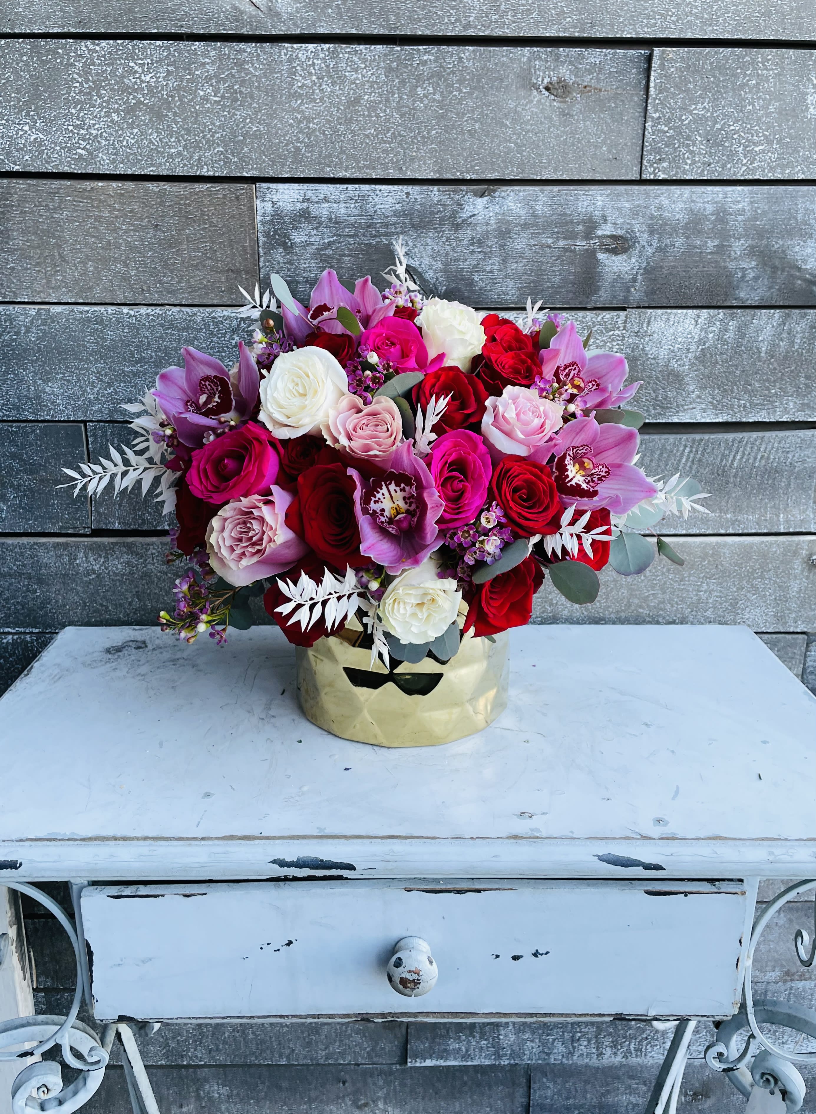 Bouquet of red, pink, white, and purple flowers in a gold container