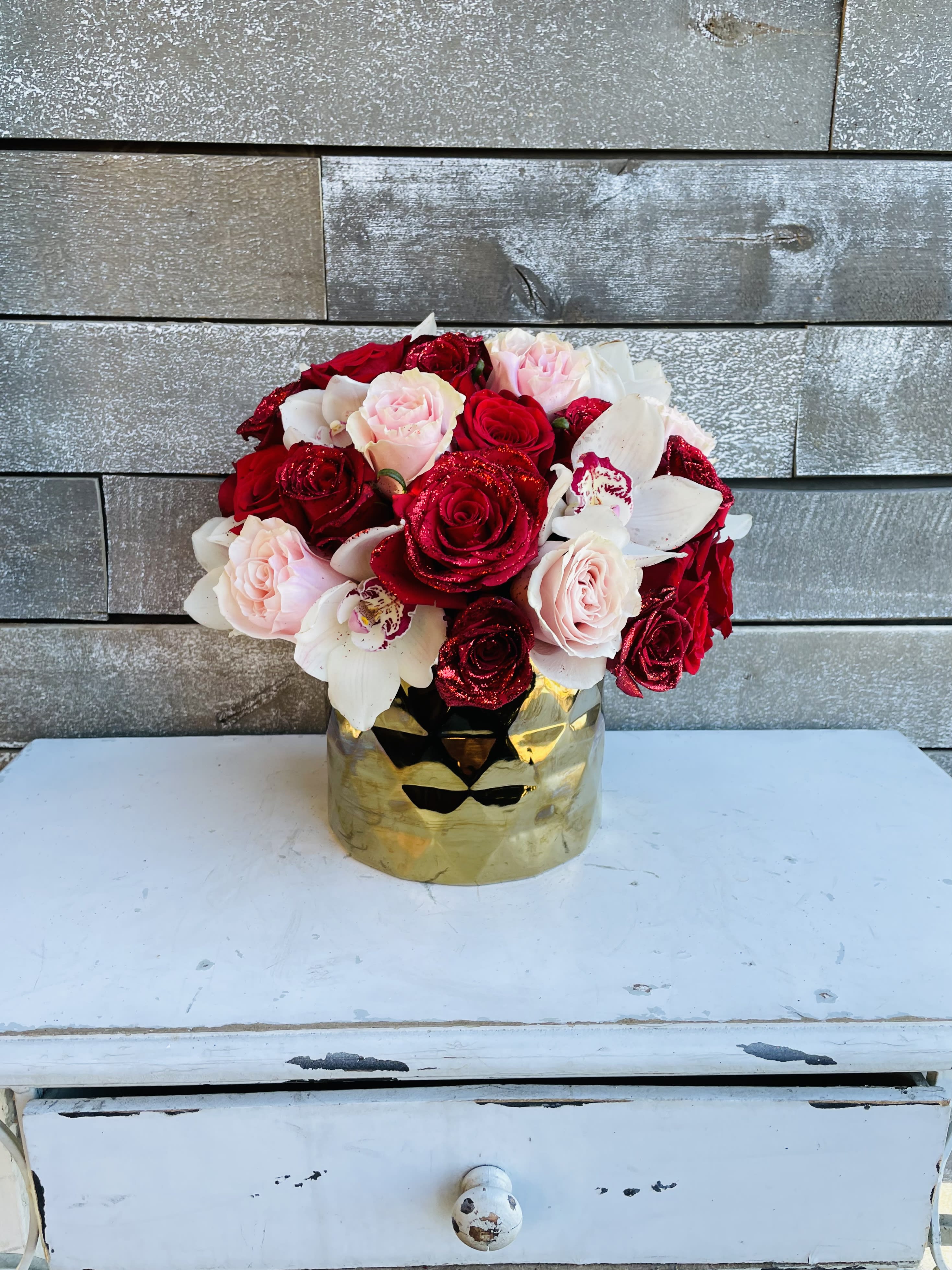 Bouquet of red, pink, and white roses in a gold vase