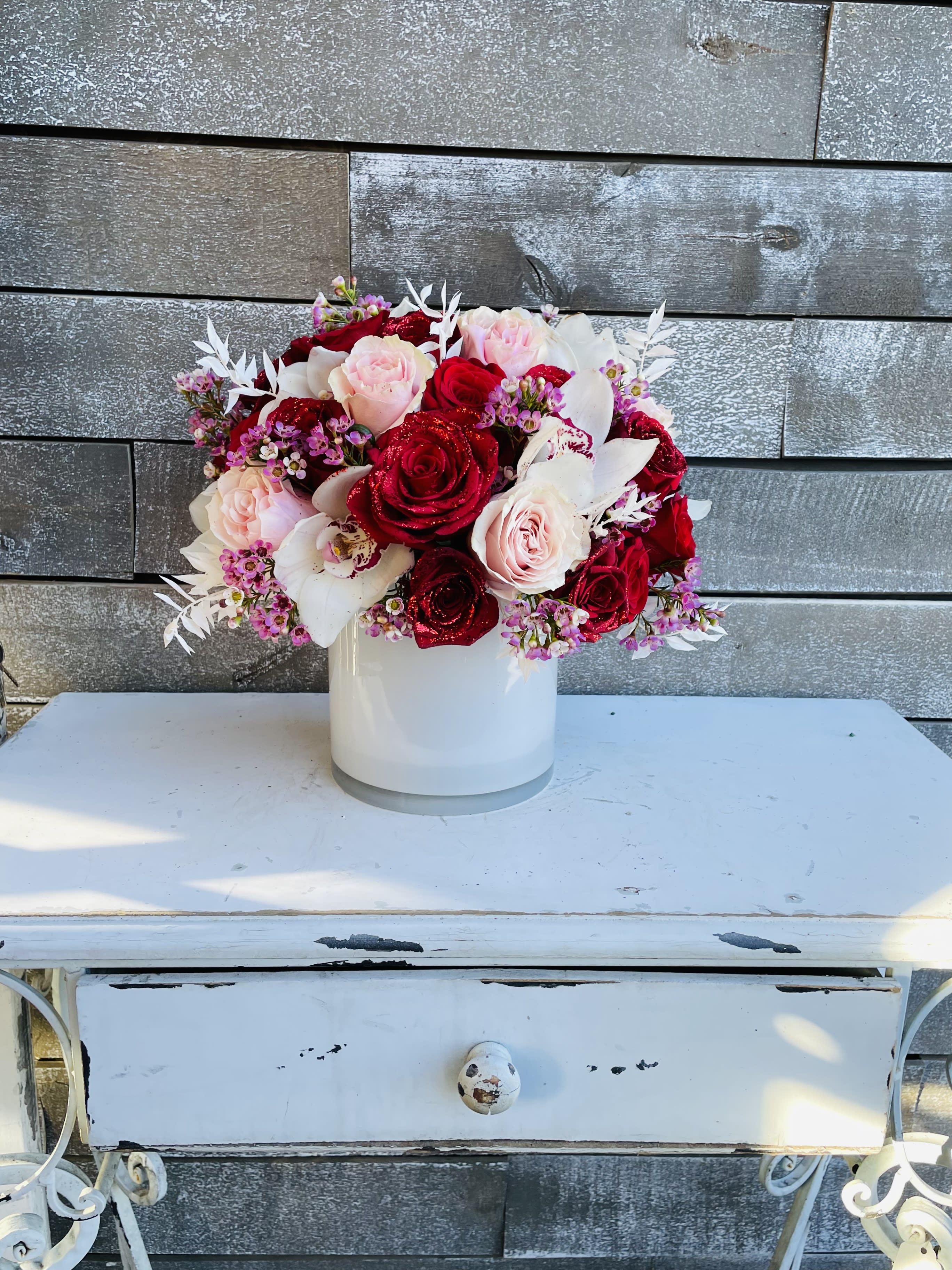 Red and blush roses arranged in a white vase